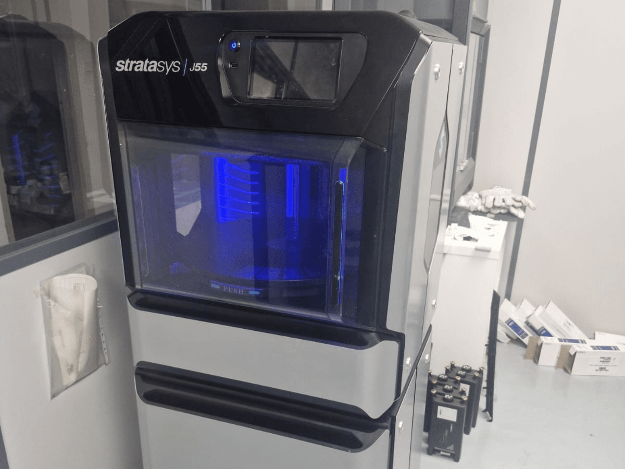 Stratasys J55 Prime -muovinen 3D-tulostin sivukuvassa, jossa näkyy sen tyylikäs muotoilu ja valaistu tulostusalue.