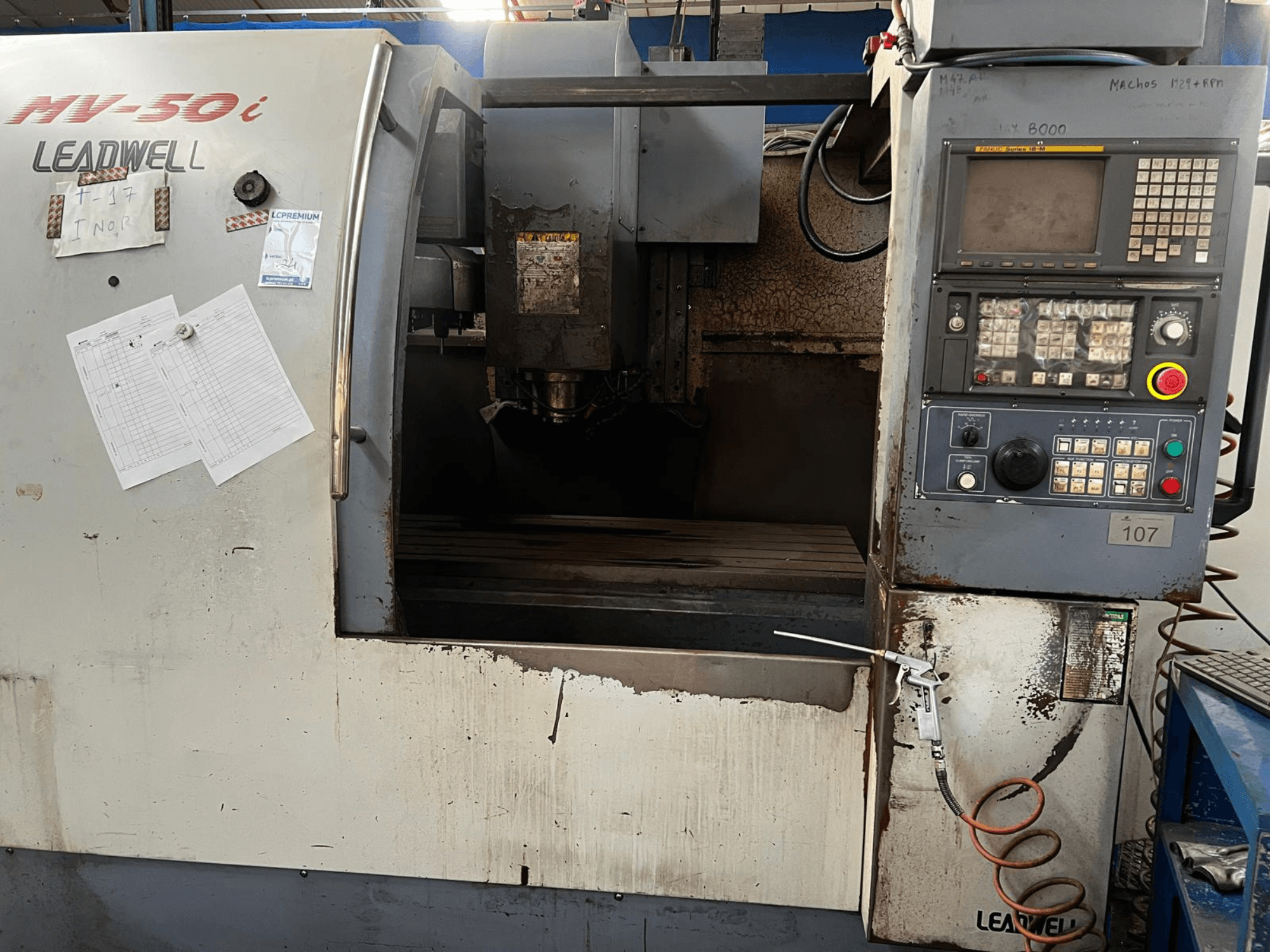 Leadwell MV-50i -pystykoneistuskeskus, etunäkymä, jossa näkyvät ohjauspaneeli, karan alue ja kulumajälkiä sisältävä työpöytä.