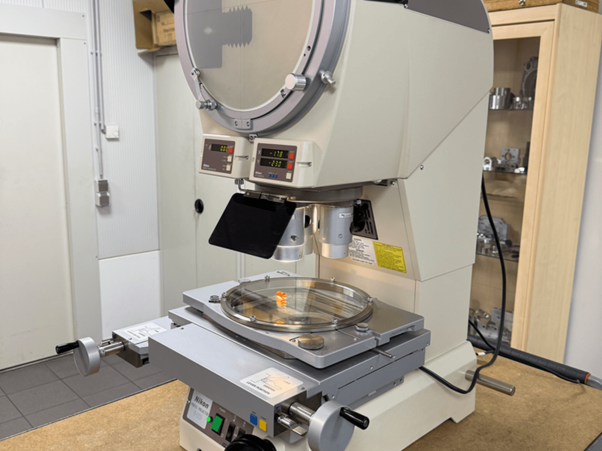 Nikon-mallin mikroskooppi etukuvasta, jossa on digitaaliset näytöt, säädettävä alusta ja pyöreä lasilevy.