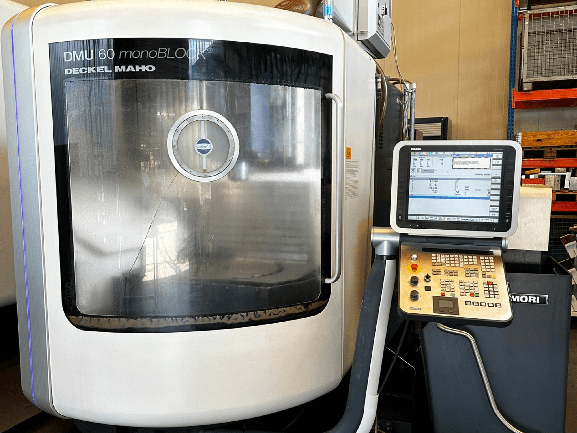 DMG MORI DMU 60 monoBLOCK -pystytyöstökeskus, etukuva, jossa näkyy kosketusnäytöllinen ohjauspaneeli ja heijastava ikkuna.