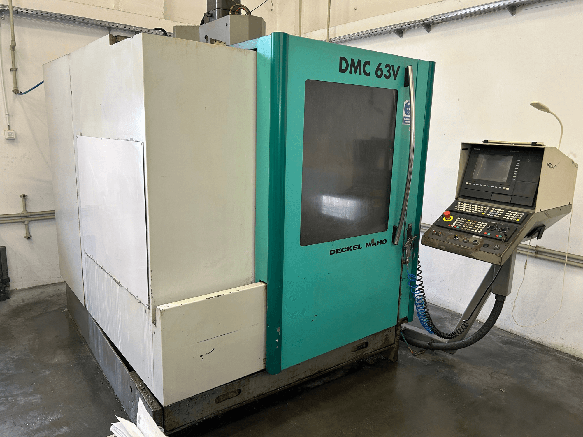 Pystytyöstökeskus DECKEL MAHO DMC 63V etukuvassa, jossa on ohjauspaneeli ja sinivihreä kotelo.