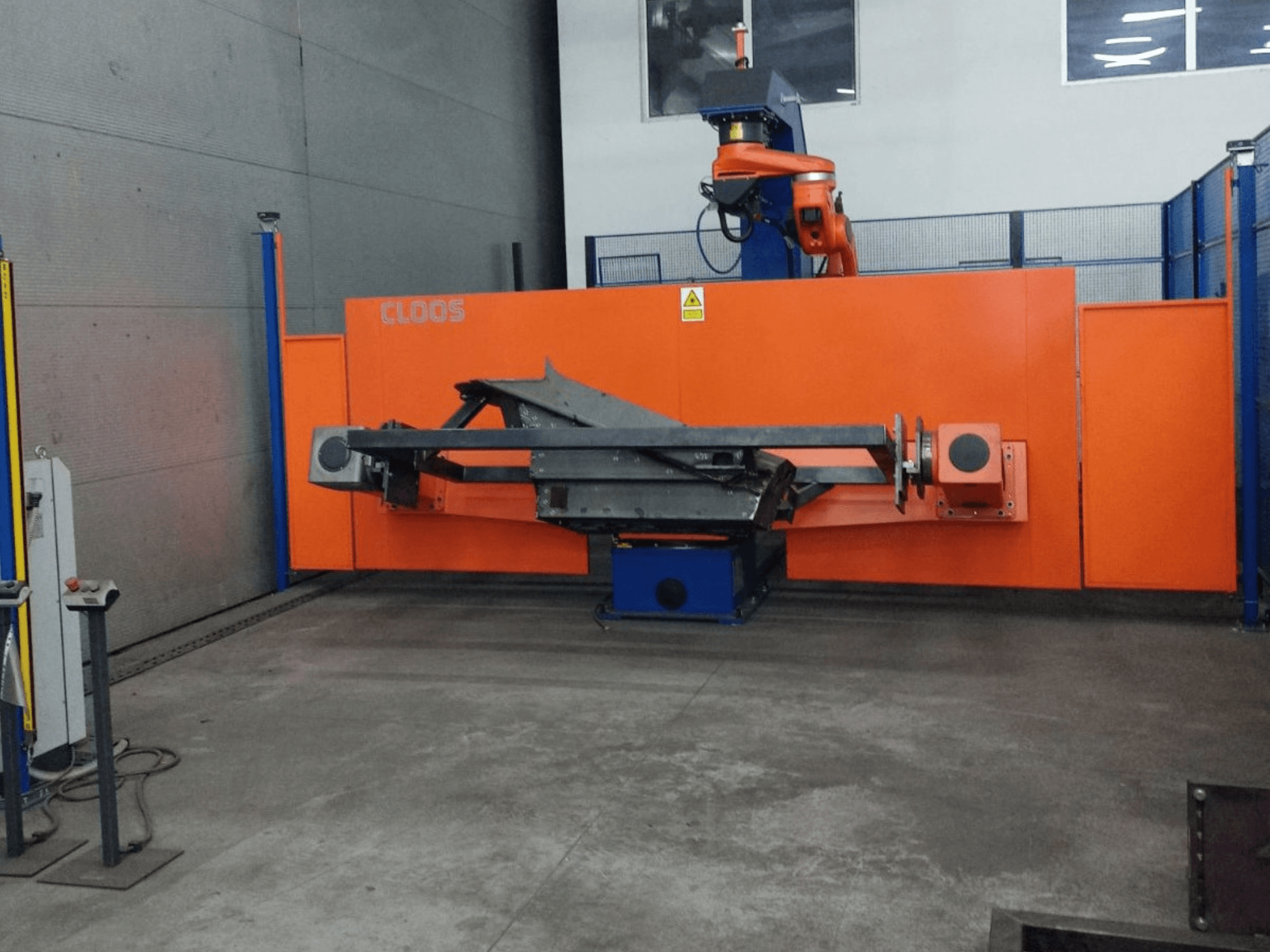 Etukuva CLOOS QIROX QRC-350-E -automaatiojärjestelmästä, jossa on robottivarsi ja metallirakenne teollisuusympäristössä.
