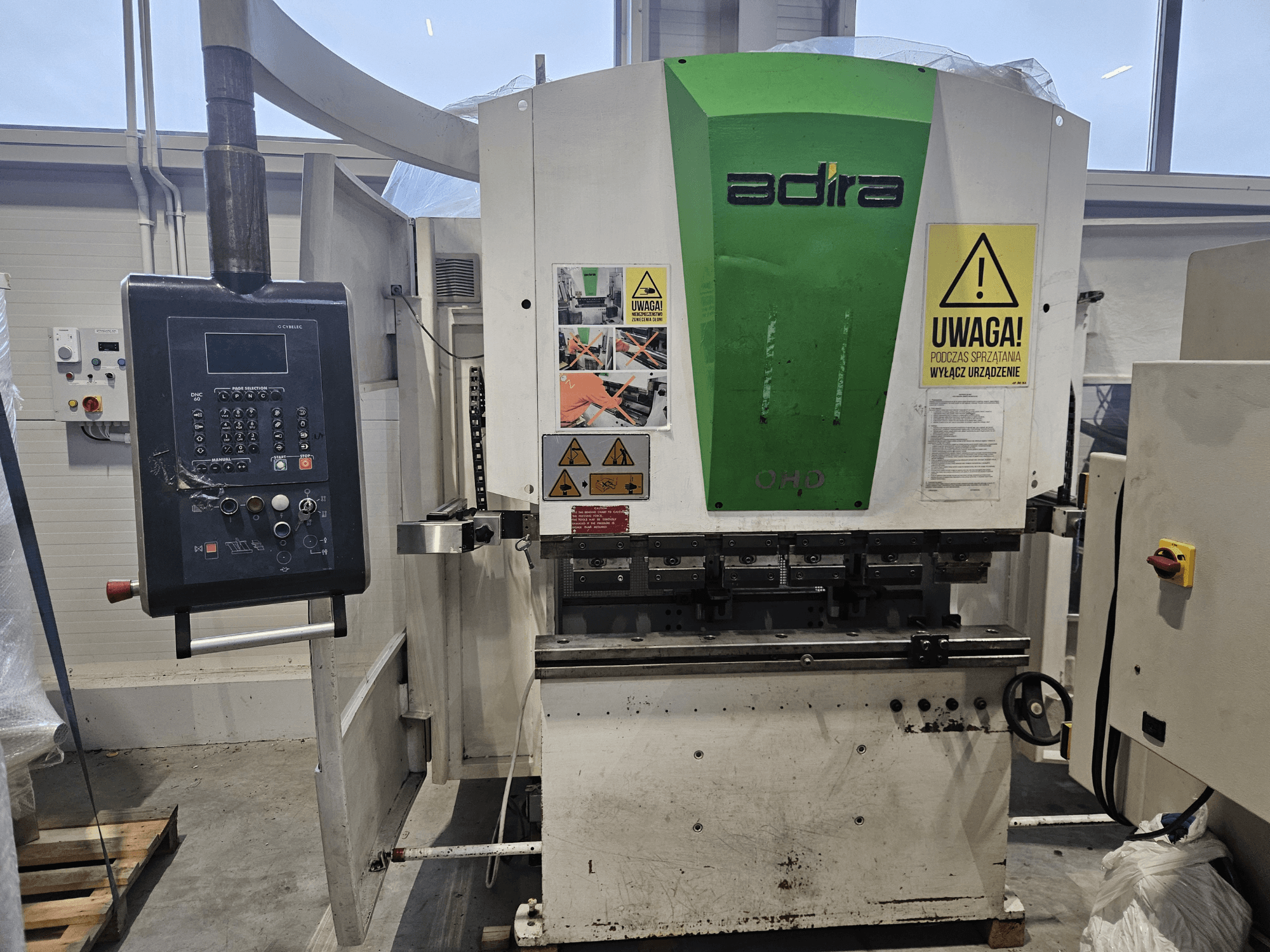 Adira OHD -kone edestä katsottuna, jossa on ohjauspaneeli, turvallisuusvaroitukset ja käyttöpainikkeet.