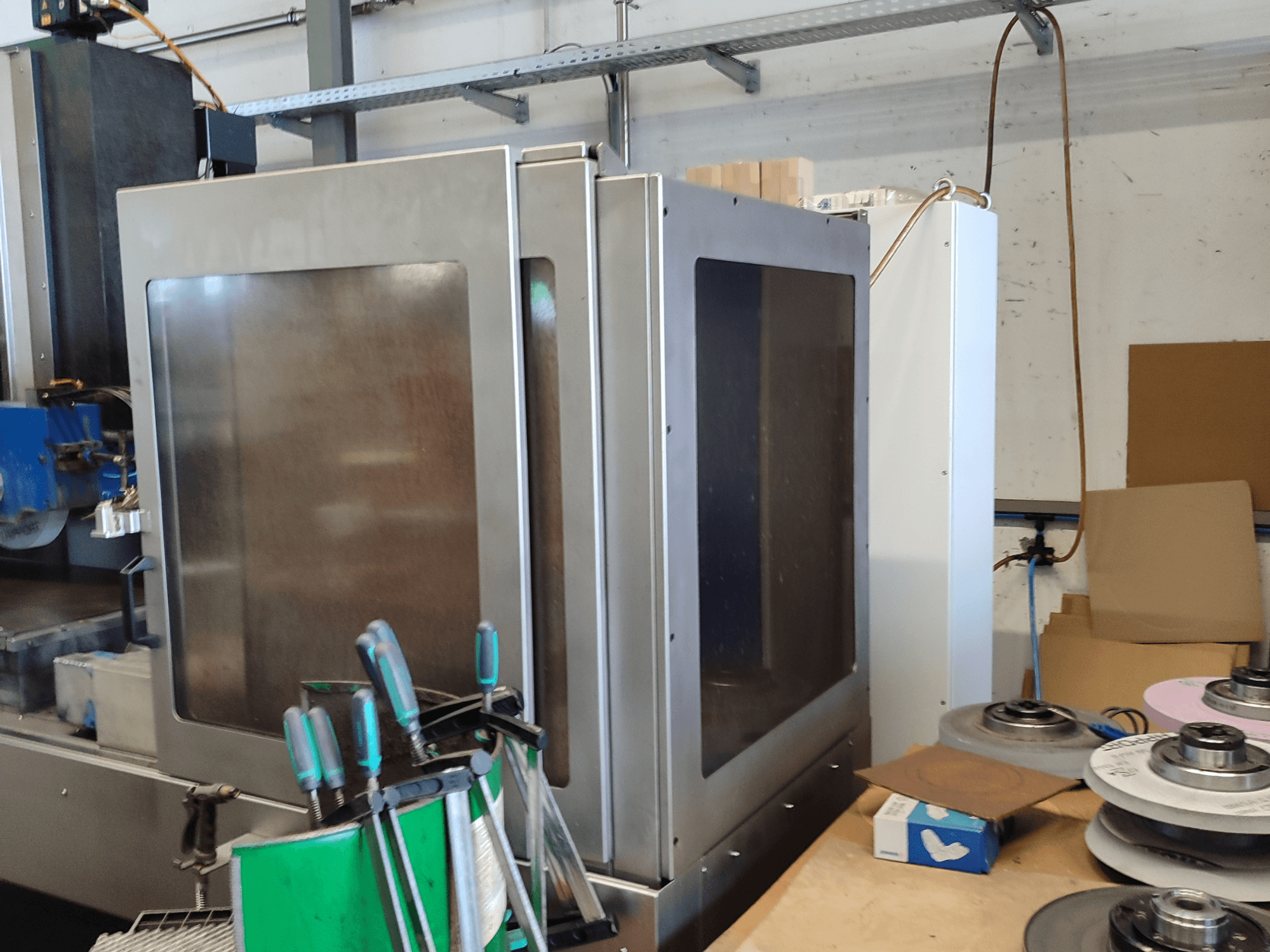 HEINZ STÖCKEL FD 1560 NC-T -pintahiontakone, sivukuva, jossa näkyy metallikotelo ja hiontakomponentit työpajatilassa.