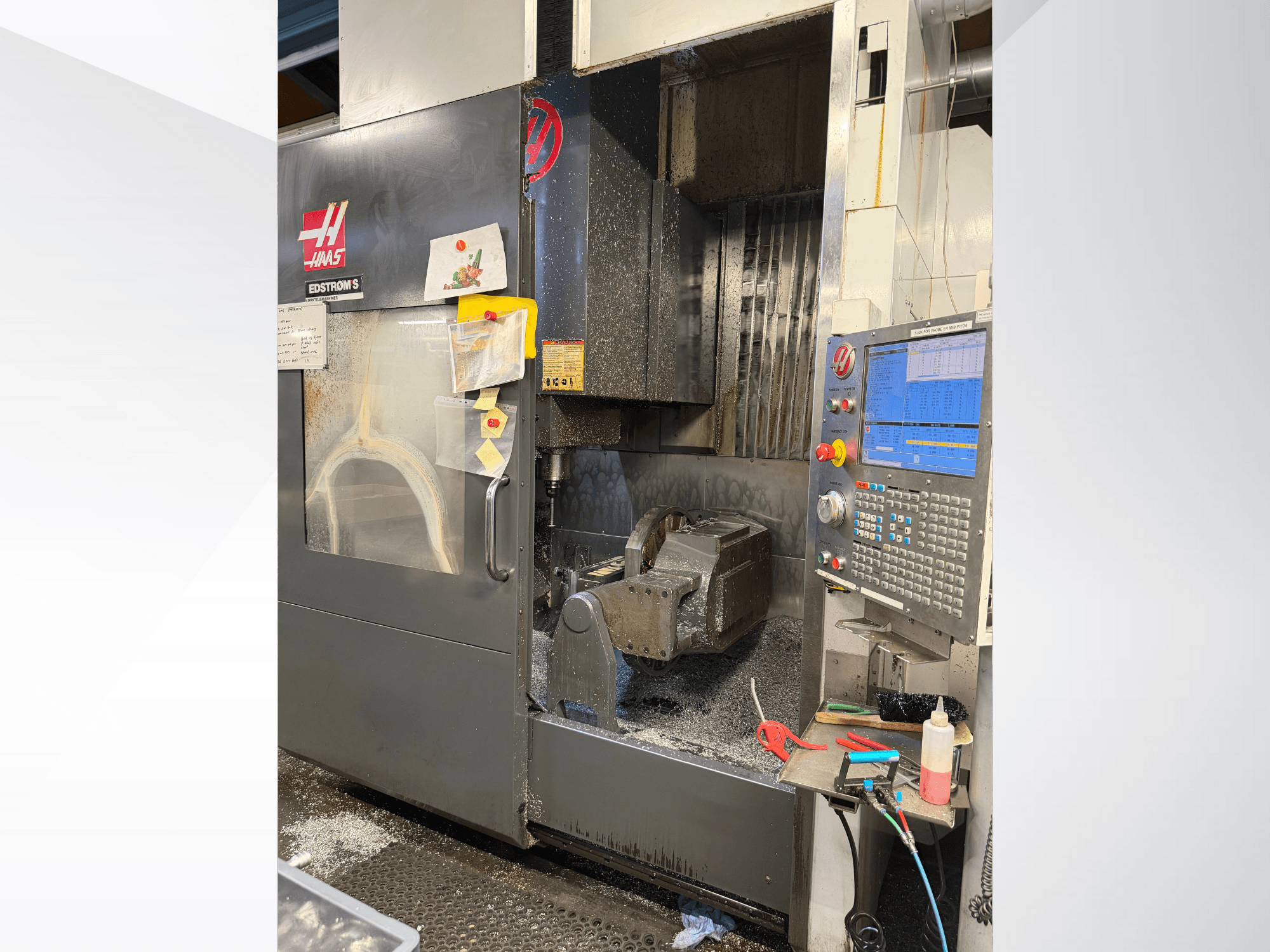 Haasin CNC-kone malli EDSTROM S, etukuva, jossa näkyy metallityökappale, ohjauspaneeli ja sisällä olevat metallilastut.