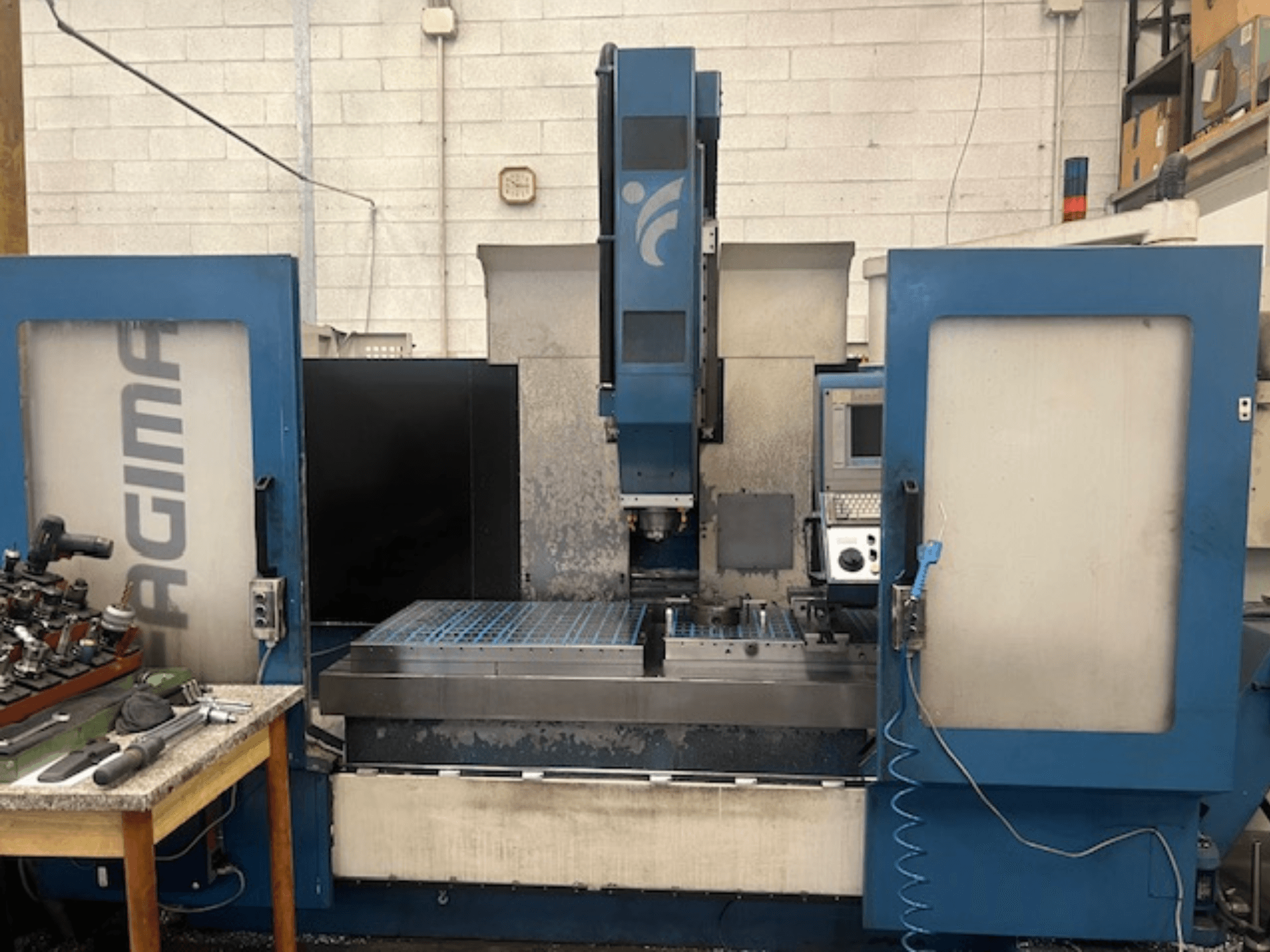 Etukuva JAGIMA CNC-koneesta, jossa on suuri metallinen työtila, näkyvä ohjauspaneeli ja työkaluja läheisellä pöydällä.