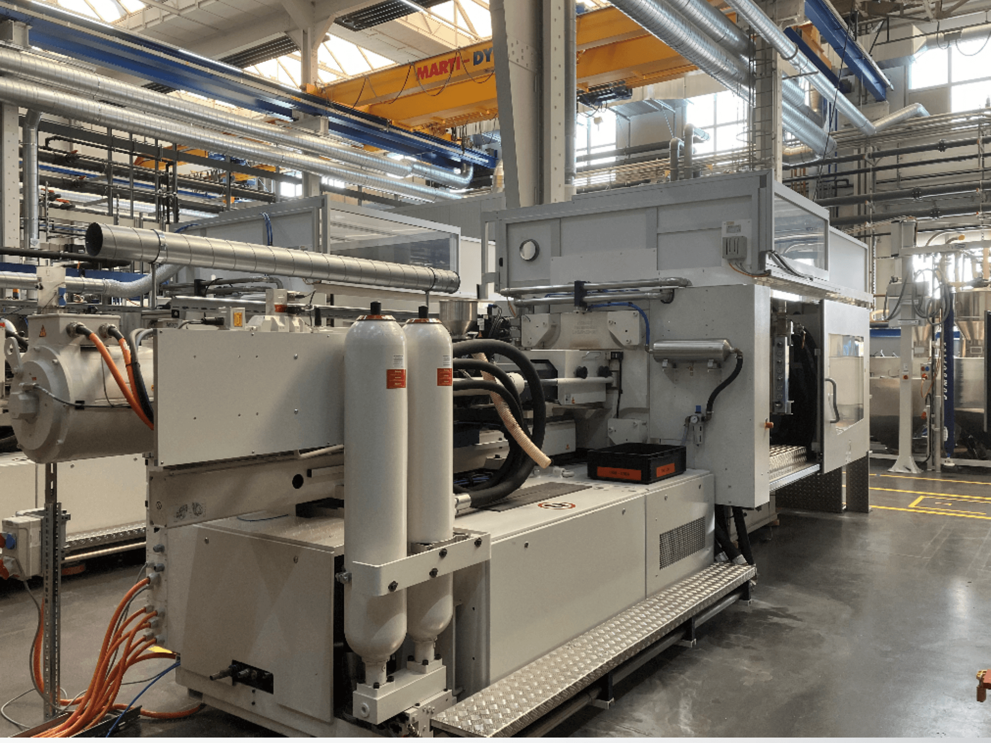 Sivukuva teollisuuskoneesta, jossa on useita letkuja, kaksi pystysuoraa säiliötä ja ohjauspaneeli; merkki/malli ei ole näkyvissä.