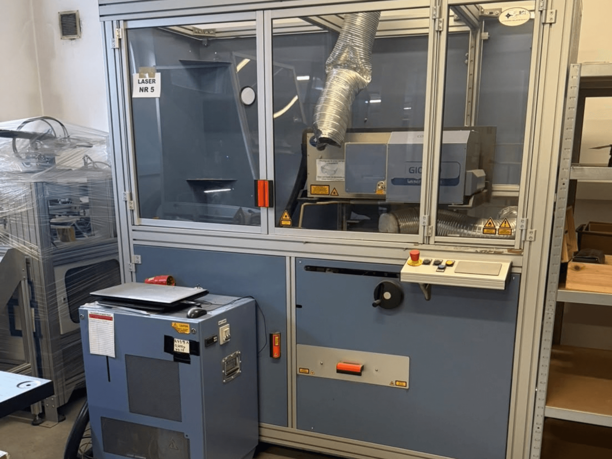 SEI Laser PAPER BLASTER 02 -CO2-laserleikkauskone, etunäkymä, jossa näkyvät ohjauspaneeli ja poistoilmakanava.