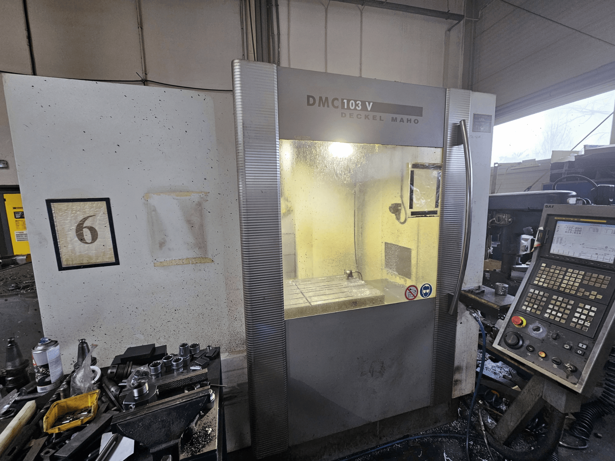 Deckel Maho DMC 103 V CNC-koneen etukuva, jossa näkyy ohjauspaneeli, työalue ja numeroitu osoitin "6".