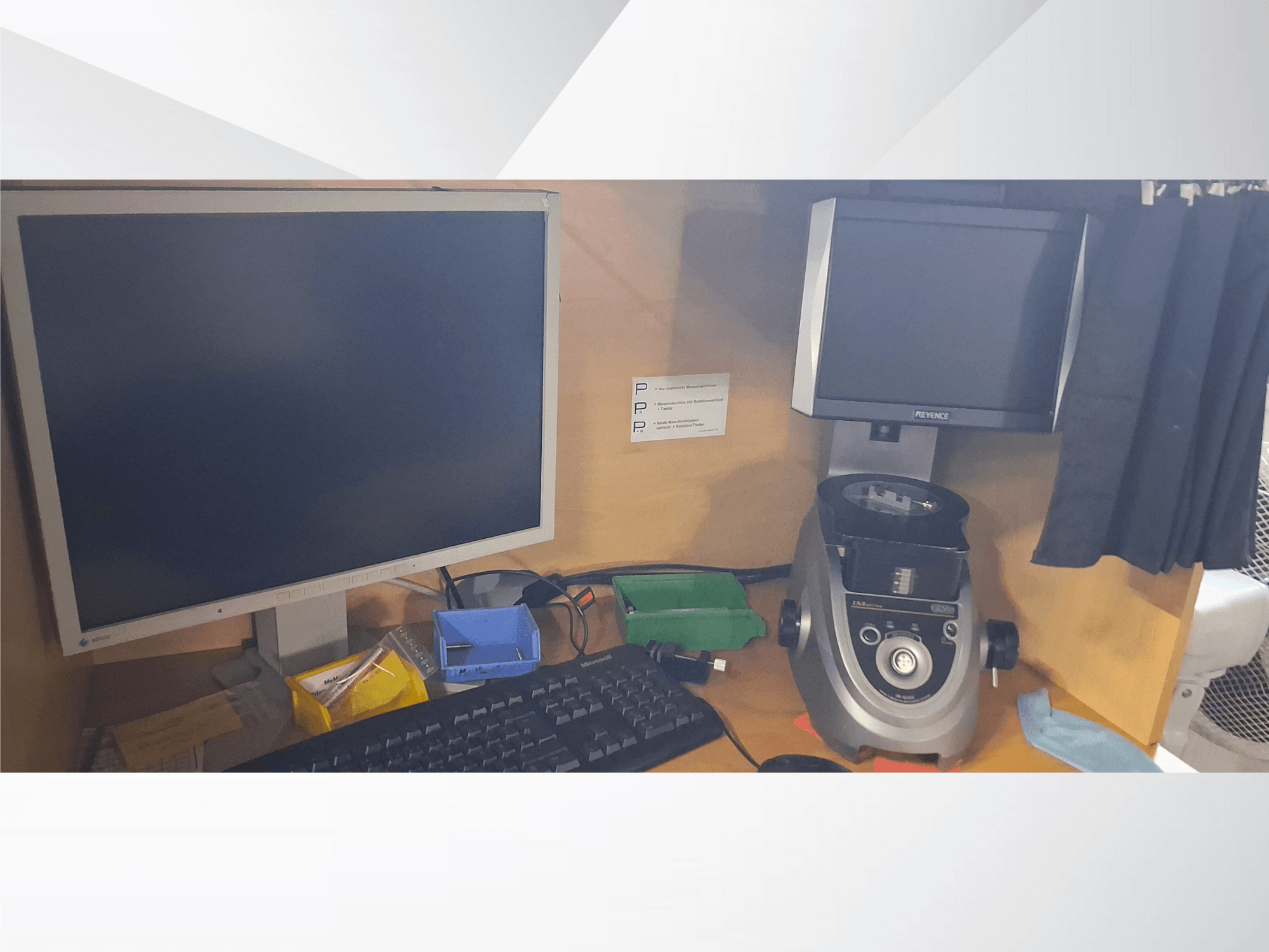 Tietokonemonitori näppäimistöllä, PEVA-merkkinen näyttö ja harmaa laboratoriolaite puisella työpöydällä, jossa on erilaisia lokeroita ja paperitöitä.