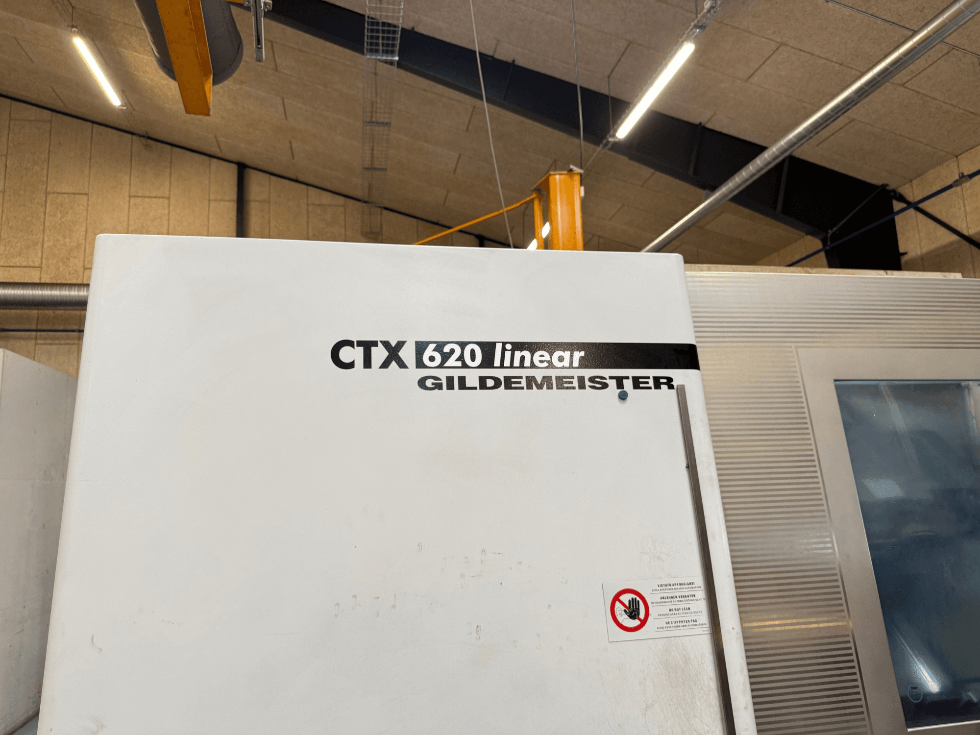 CTX 620 Linear Gildemeister -koneen sivukuva, jossa on valkoinen ulkopinta ja varoituskilvet.