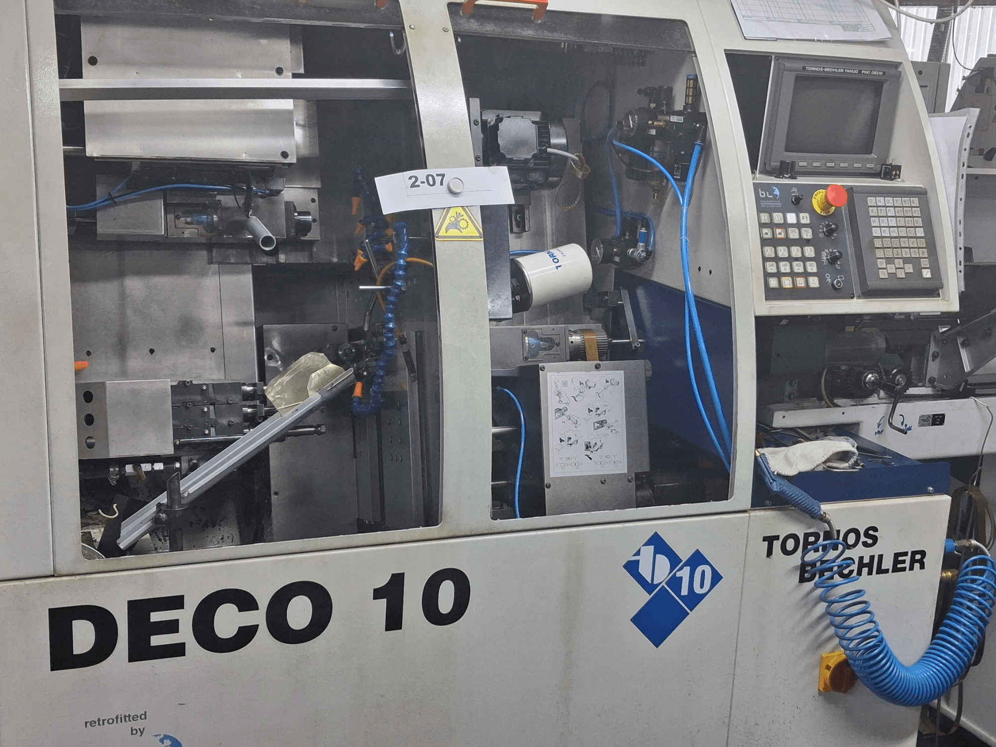 TORNOS Deco 10a sveitsiläistyyppisen sorvauskoneen lähikuva, jossa näkyy sisäisen mekanismin ja ohjauspaneelin yksityiskohdat.