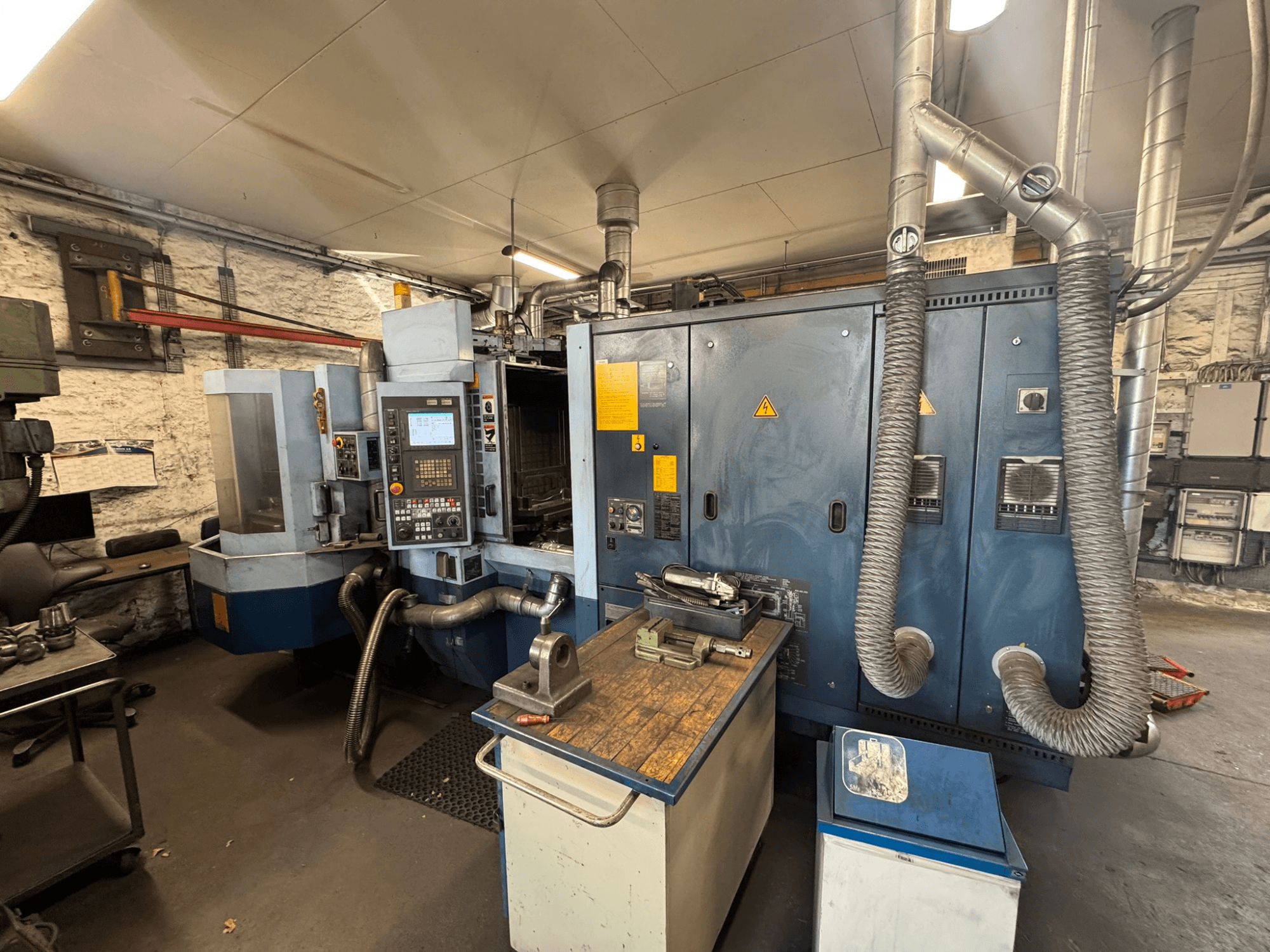 Matsuura H.PLUS-300 -vaakakoneistuskeskus työpajassa, etunäkymä, jossa näkyvät ohjauspaneeli ja työpöytä.