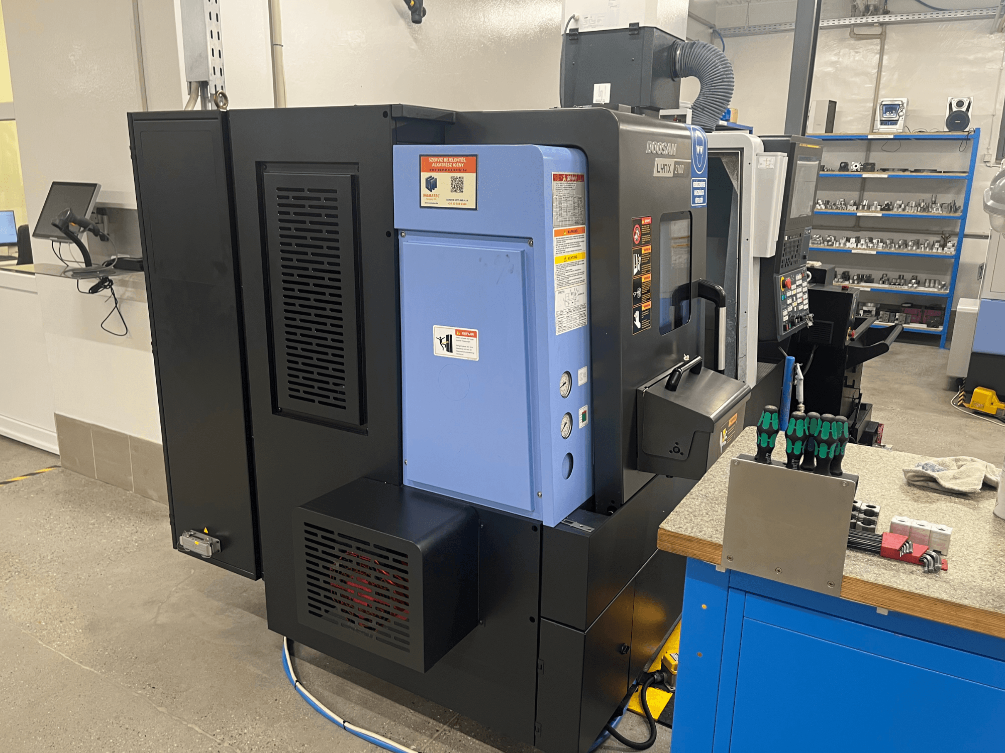 Doosan Lynx 2100 -sorvi, sivukuva, jossa näkyy ohjauspaneeli, ilmanvaihtojärjestelmä ja työkalut työpöydällä.