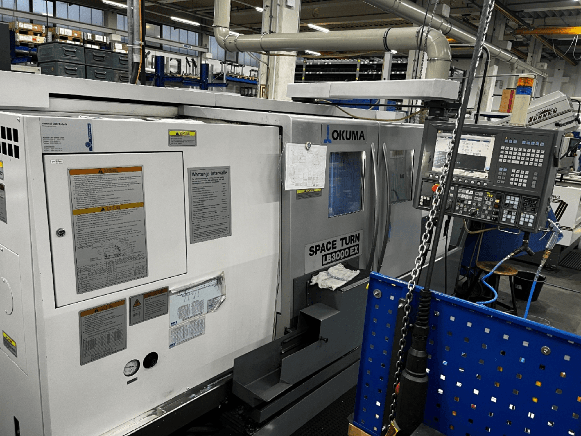 Okuma LB3000 EX vaakasuuntainen sorvauskone, etukuva, jossa on ohjauspaneeli ja turvallisuustiedot sivulla.