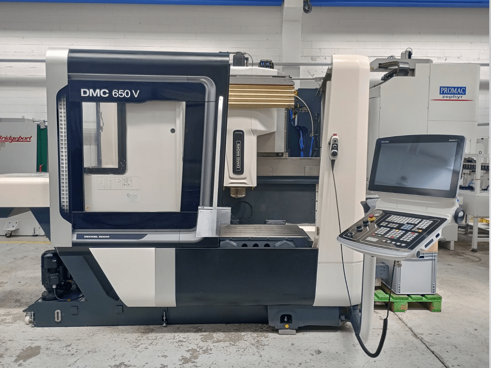 Decker Maho DMC 650 V CNC-koneen sivukuva, jossa on ohjauspaneeli, jossa on painikkeita ja näyttö, teollisuusympäristössä.
