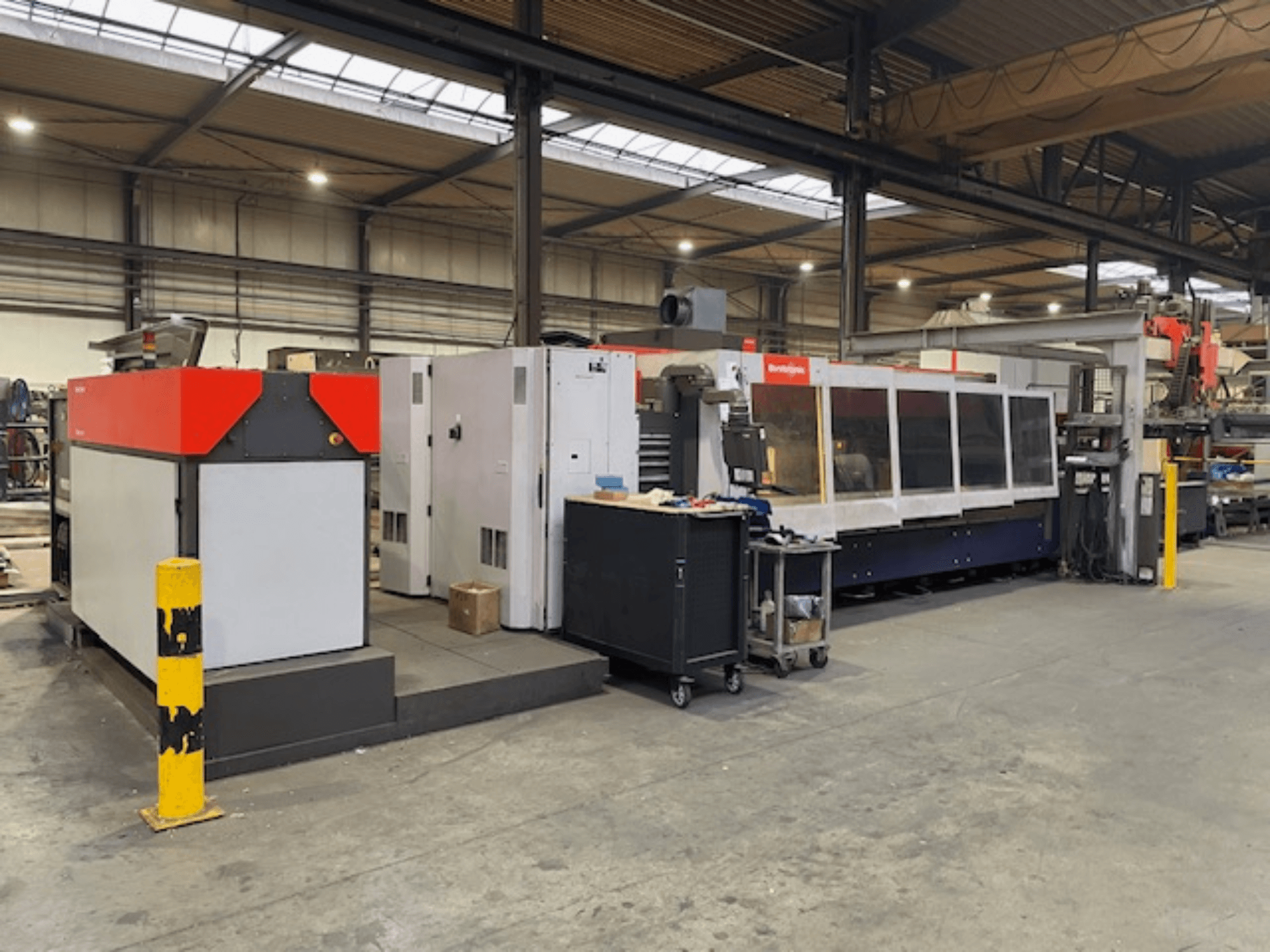 Bystronic BySpeed 3015 CO2-laserleikkauskone, sivukuva työpajassa, jossa on punaisia ja harmaita muotoiluelementtejä.