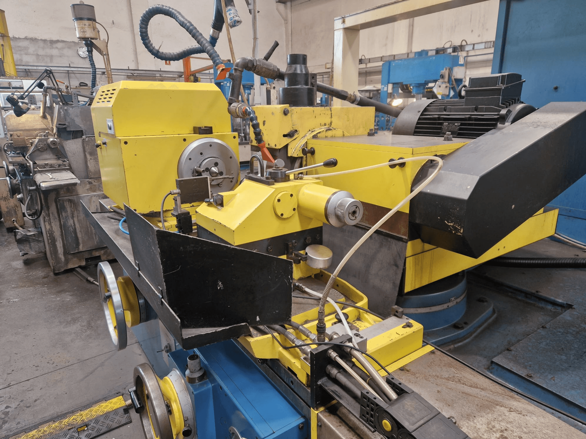 Keltainen teollisuuskone, jossa on musta osa, jossa on asteikko ja letkut, edestä katsottuna pienessä kulmassa.