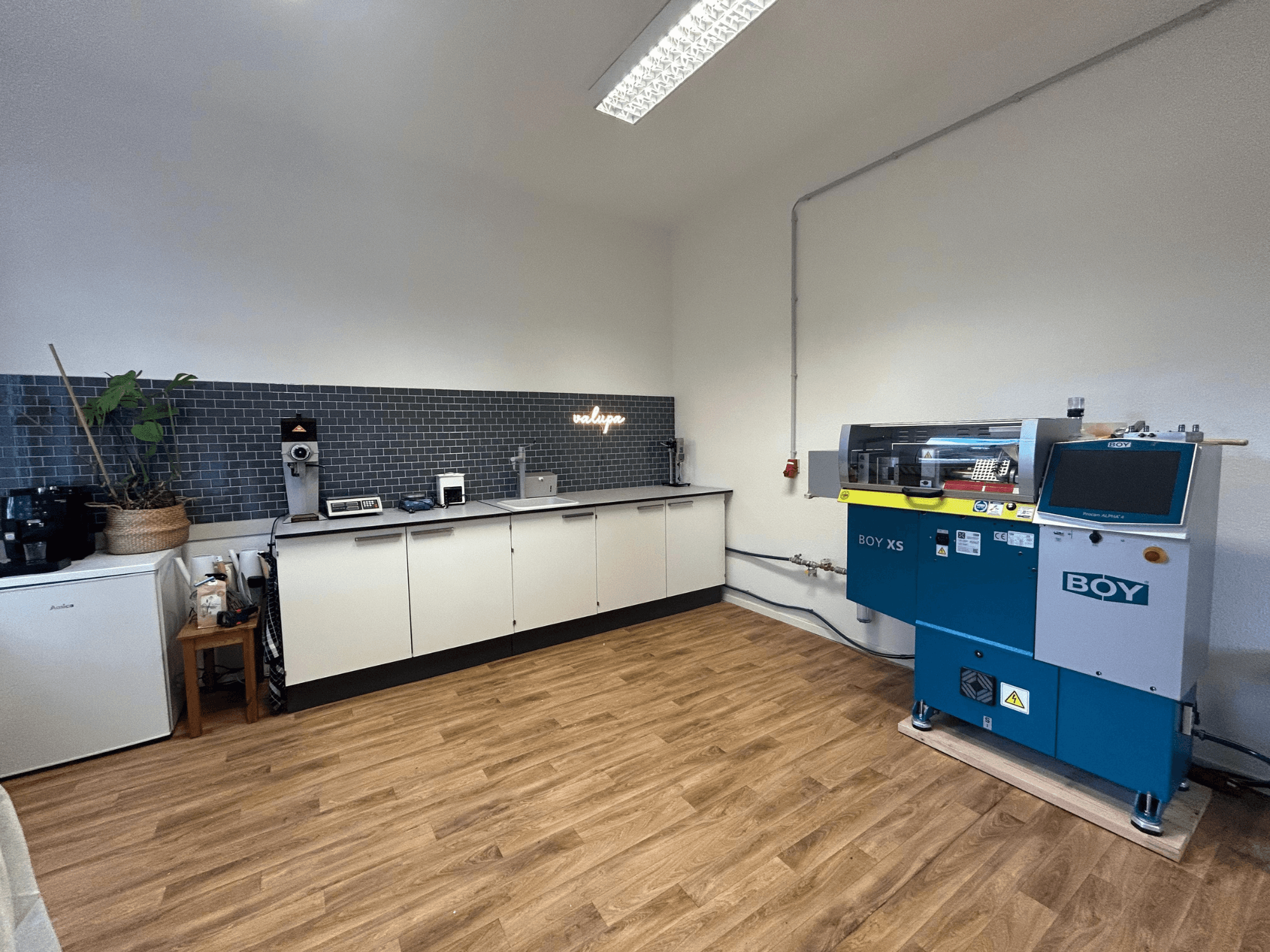 Hydraulinen ruiskuvalukone BOY XS 161, etukuva, modernissa keittiöympäristössä, jossa on kodinkoneet ja puulattia.