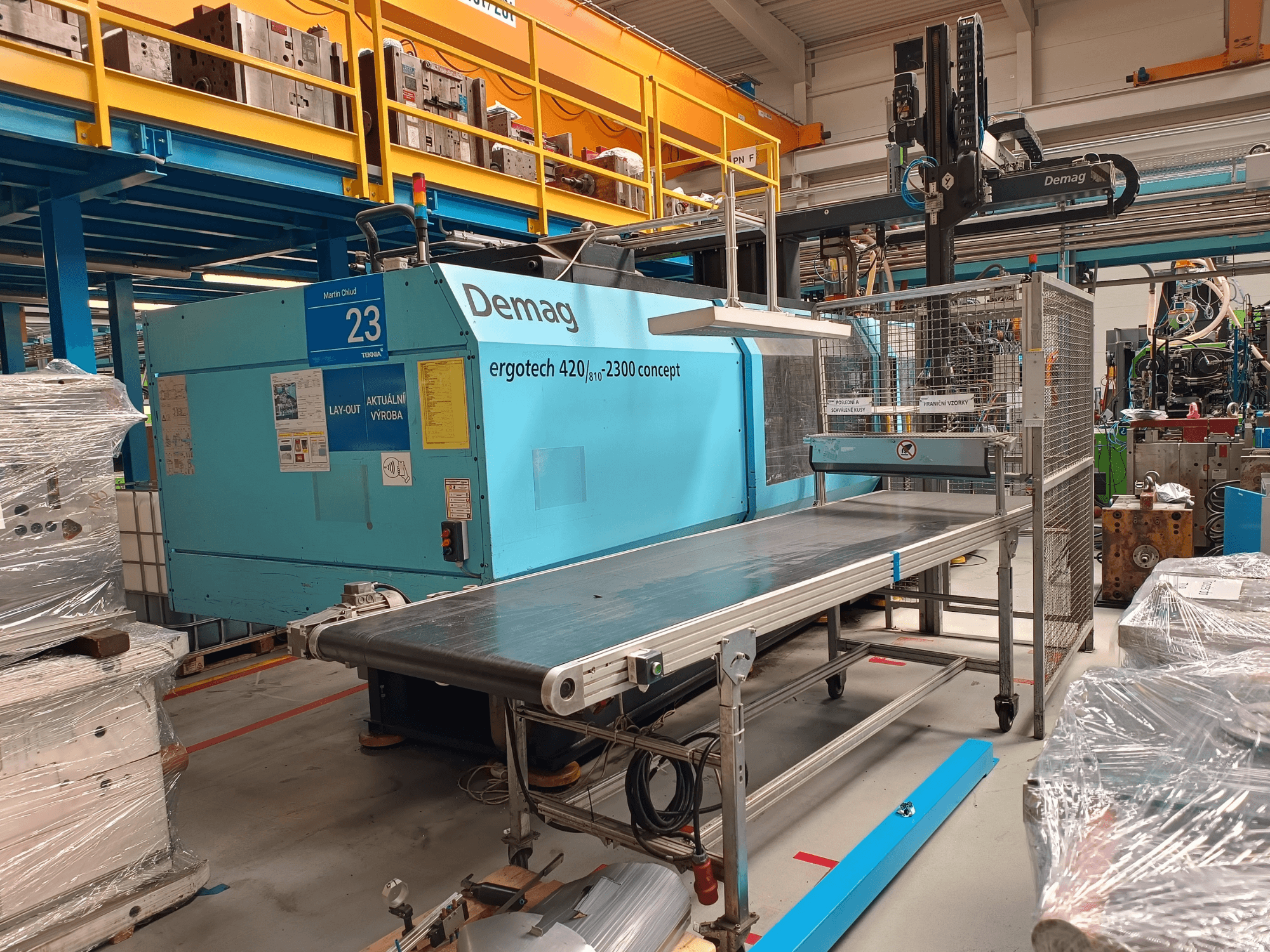 Demag ergotech 420/810 - 2300 hydraulinen ruiskuvalukone sivukuvassa, jossa on kuljetin ja turvakotelo.