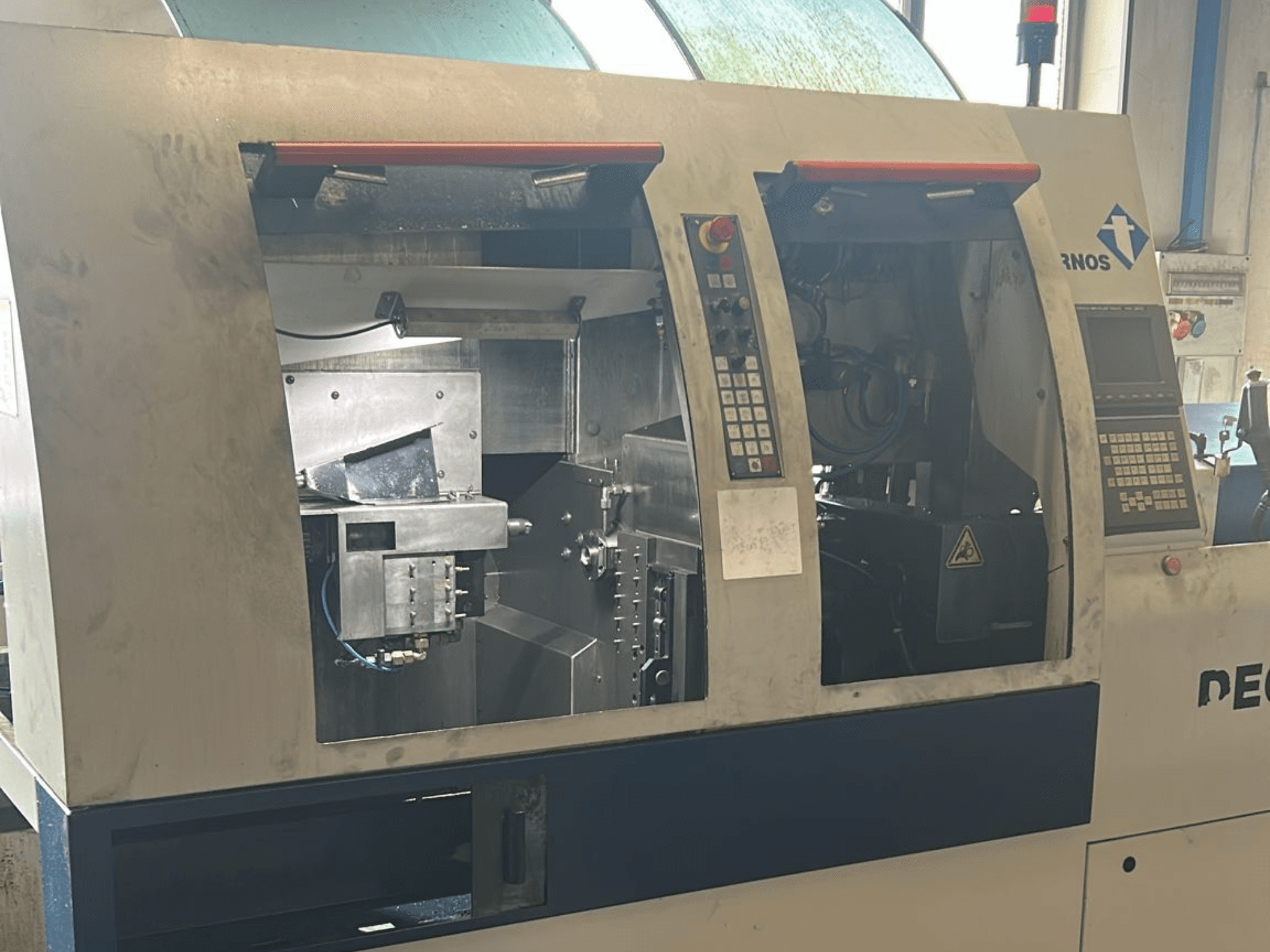 Alt-teksti: TORNOS Deco 13 b sveitsiläistyyppisen sorvauskoneen etukuva, jossa ohjauspaneelit ja sisäiset komponentit näkyvissä.