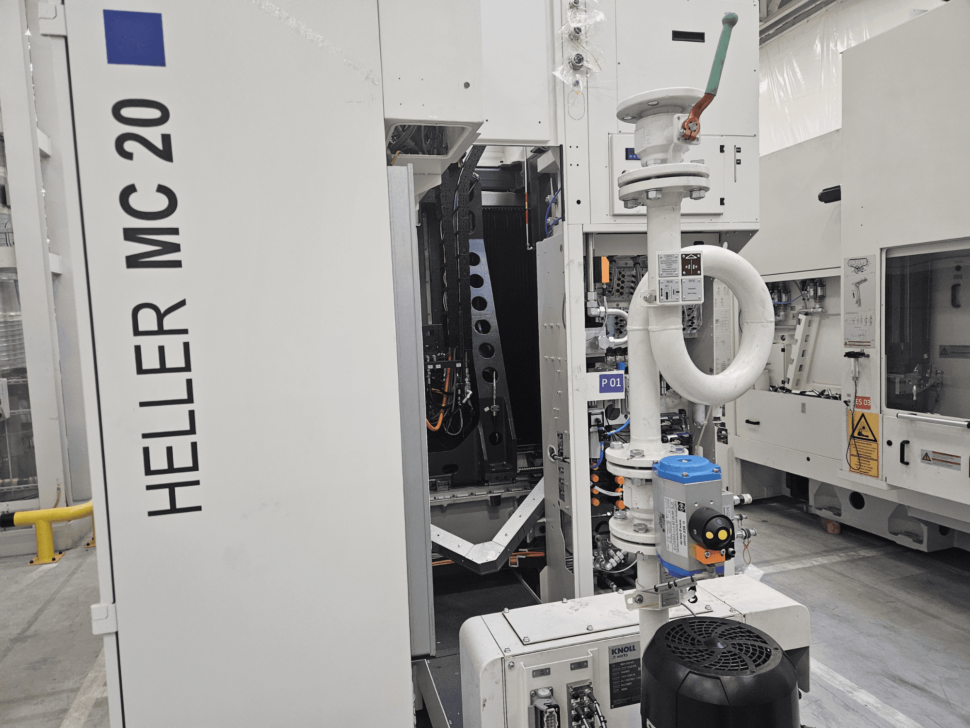 Heller MC 20 -kone tehdasympäristössä, jossa näkyy ohjauspaneeli ja mekaaniset osat sivulta katsottuna.