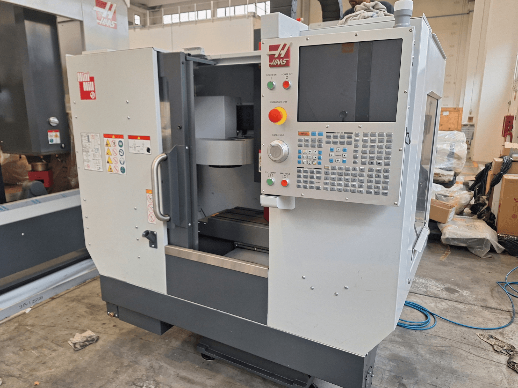 HAAS Mini Mill -pystykoneistuskeskus edestä katsottuna; kuvassa näkyy ohjauspaneeli, jossa on painikkeita ja näyttöruutu.