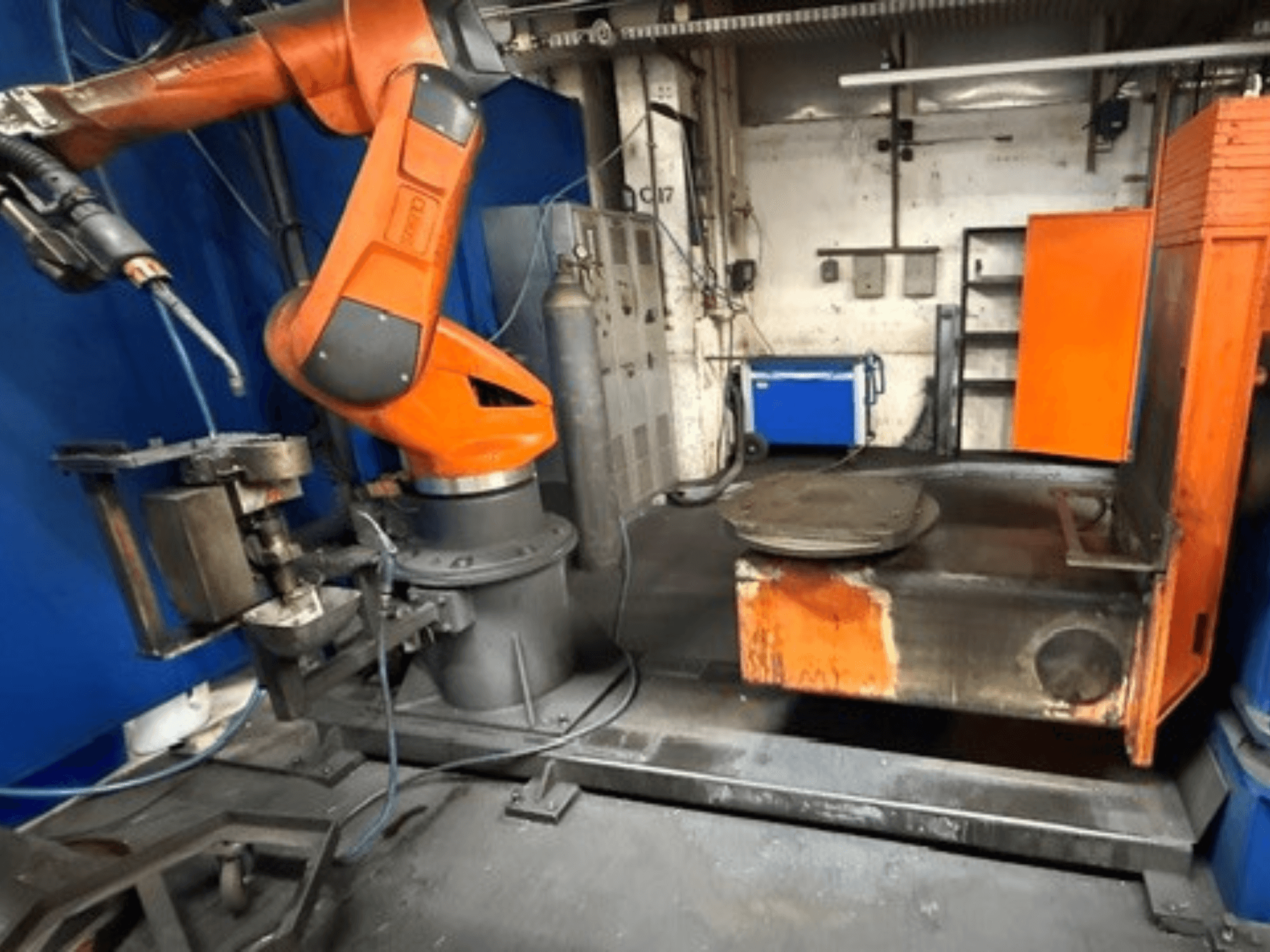 CLOOS C50 -hitsausrobotti edestä katsottuna; siinä on oranssi robottivarsi ja metallinen työpöytä.