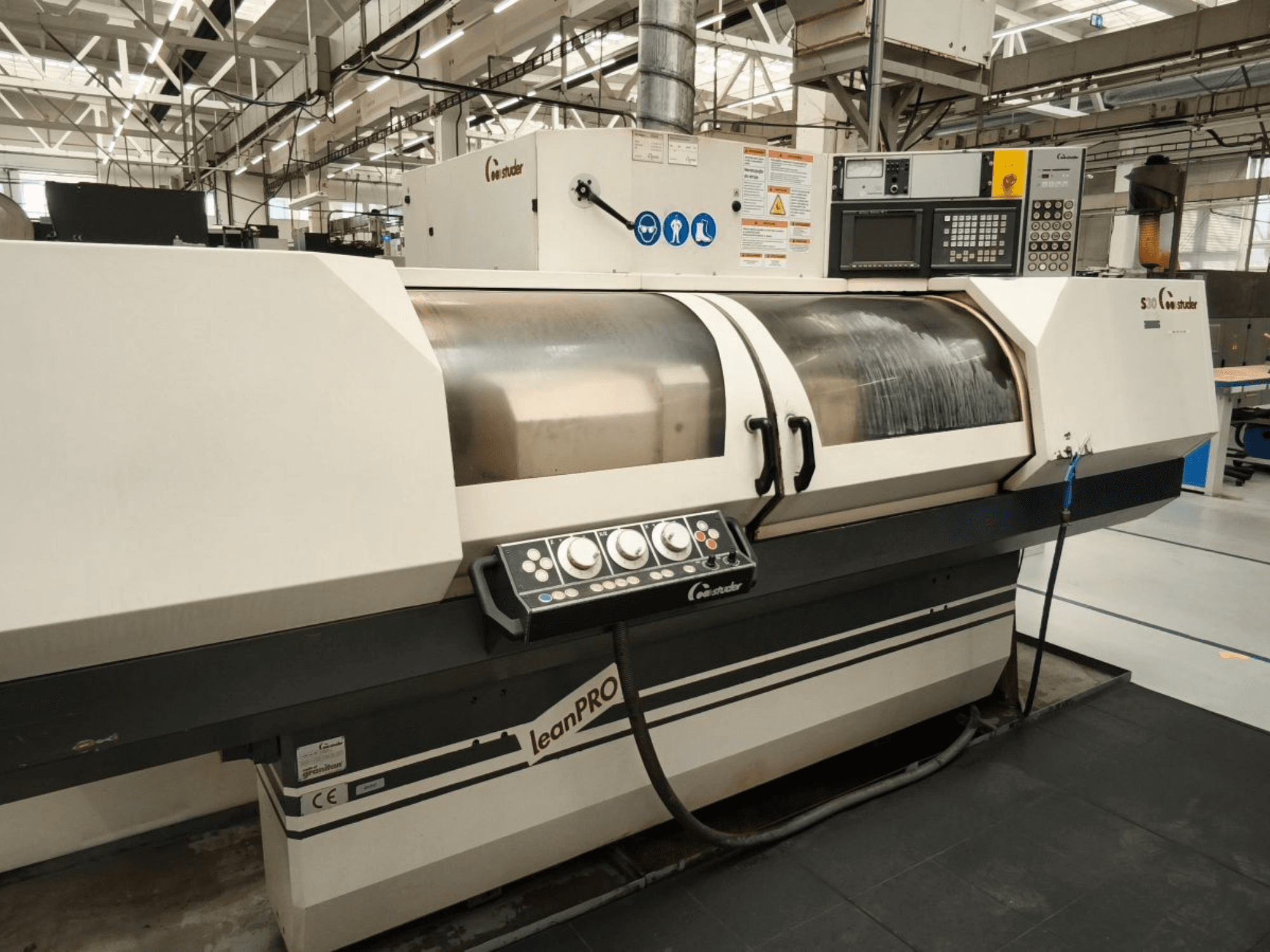 STUDER S30 LEAN PRO -lieriöhiomakone, sivukuva, jossa näkyy ohjauspaneeli ja hiomalaikan suojus teollisuusympäristössä.