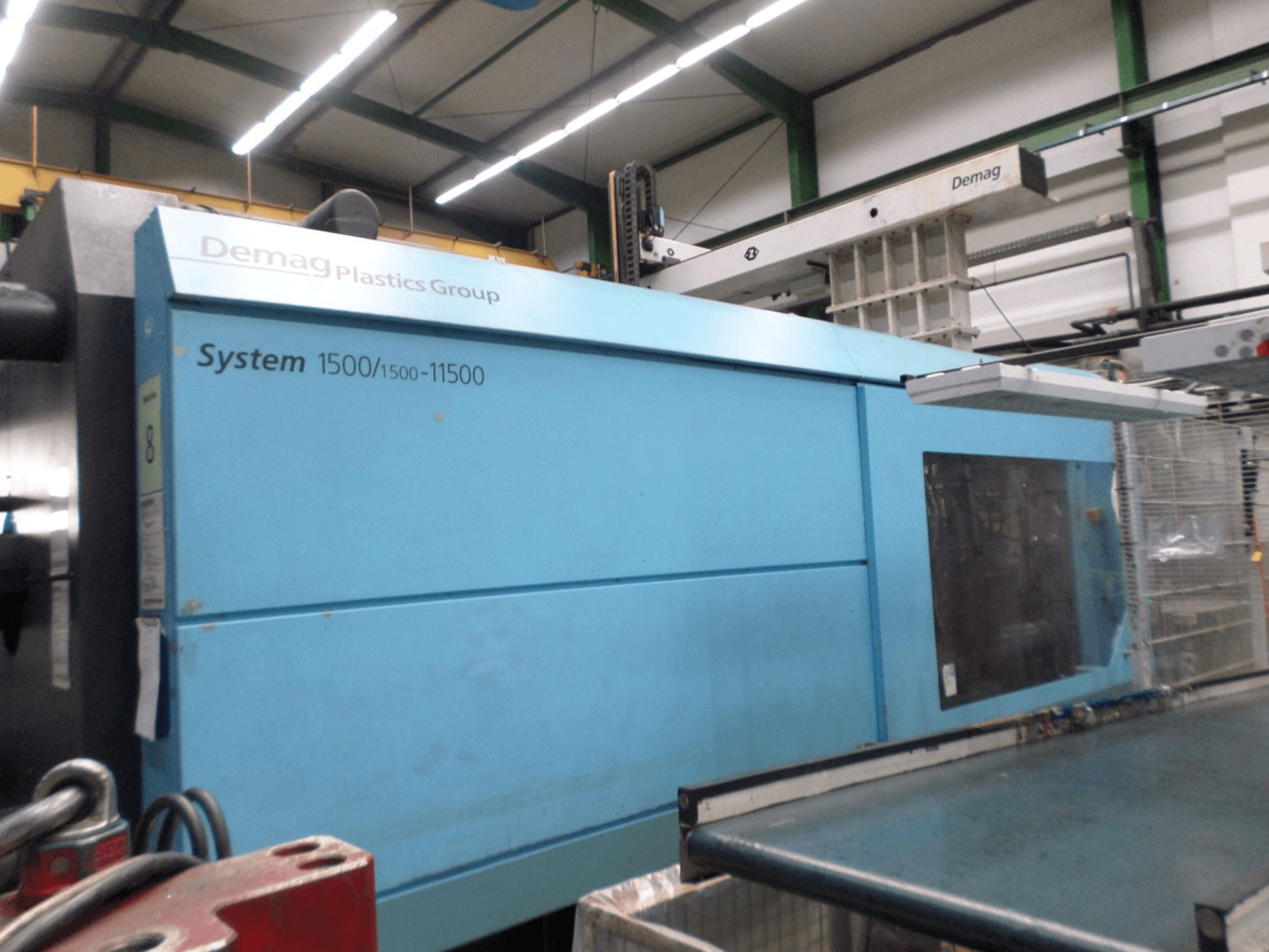 Sininen Demag D 650 -hydraulinen ruiskupuristuskone, sivukuva, jossa näkyy System 1500/1500-11500 -tarra ja käyttöalue.