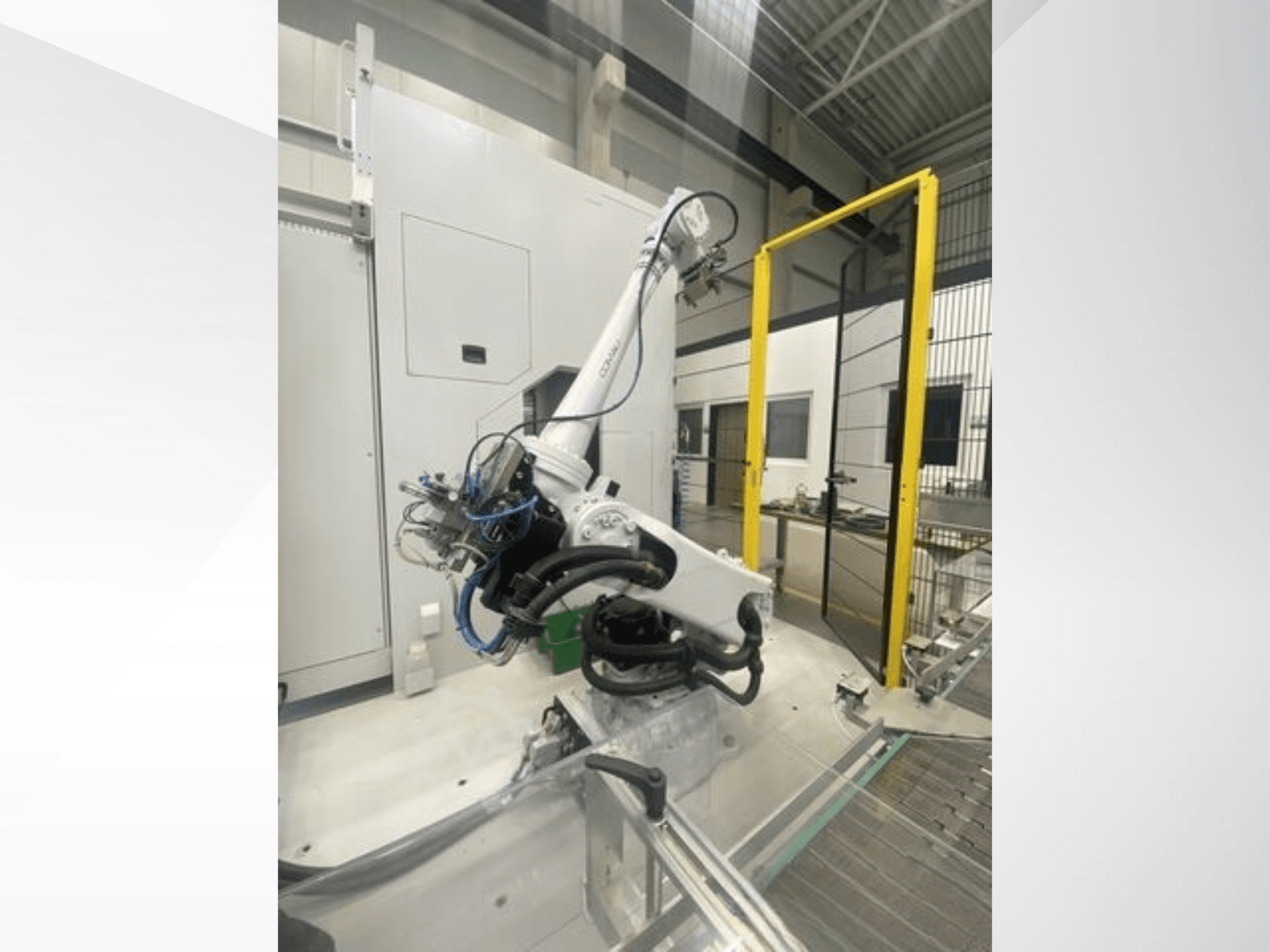 COMAU Smart NJ 40-2.5 -robottivarsi sivukuvassa, jossa on kaapelit ja keltainen turvaportti tehdasympäristössä.