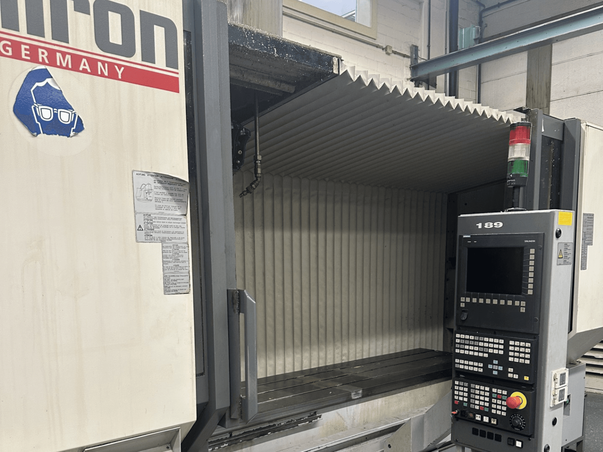 Alt-teksti: Etukuva Hermle CNC-koneesta, jossa on ohjauspaneeli, jossa on painikkeet ja näyttö, ja jossa on avoin työskentelyalue.