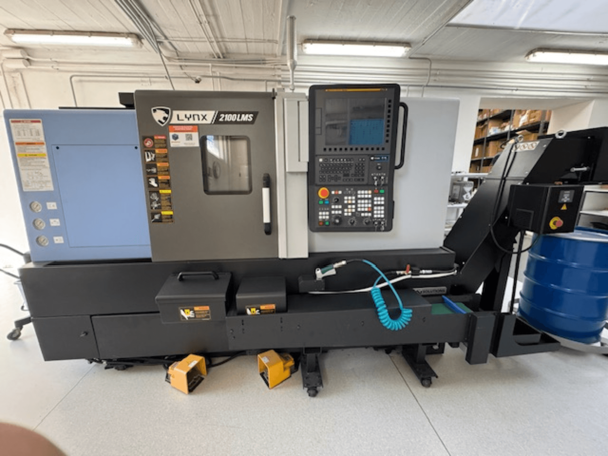 DOOSAN LYNX 2100LMSA vaakasuora sorvauskone, etukuva, jossa on ohjauspaneeli, jäähdytysnesteletku ja säilytyslaatikot.
