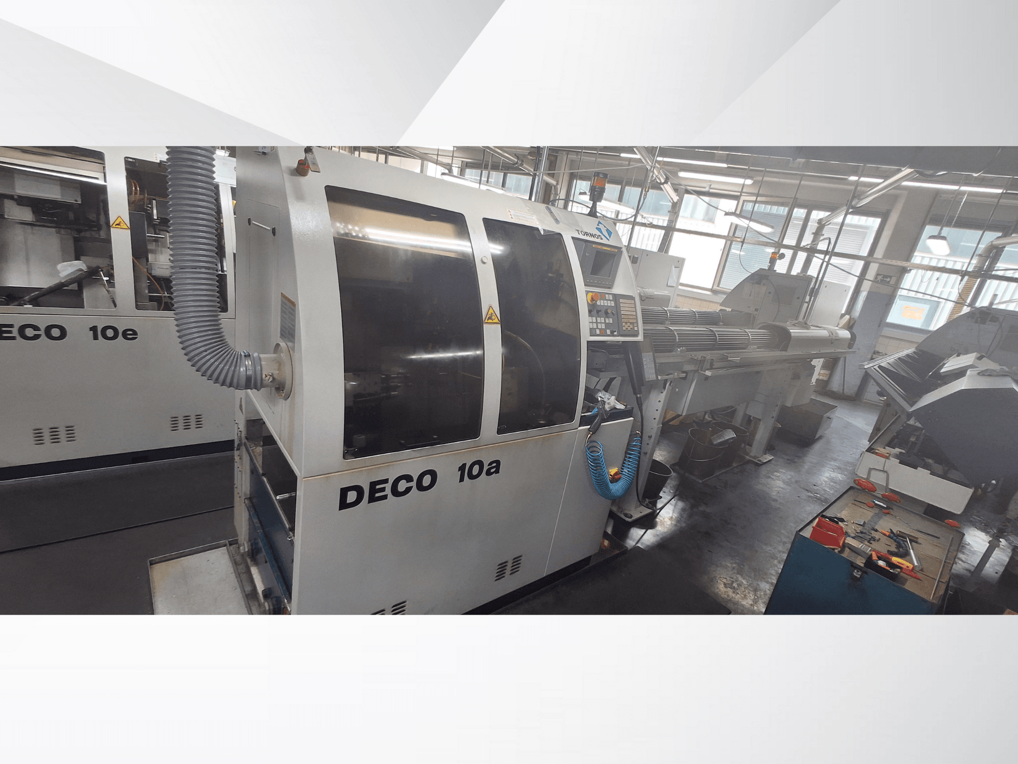 DECO 10a CNC-kone työpajassa, jossa näkyy etukuva, ohjauspaneeli ja pakojärjestelmä. Järeä rakenne ja tarkkuutta vaativat työkalut.