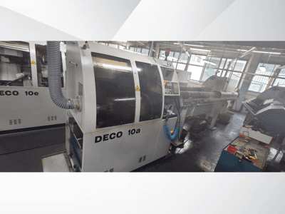 DECO 10a CNC-kone työpajassa, jossa näkyy etukuva, ohjauspaneeli ja pakojärjestelmä. Järeä rakenne ja tarkkuutta vaativat työkalut.
