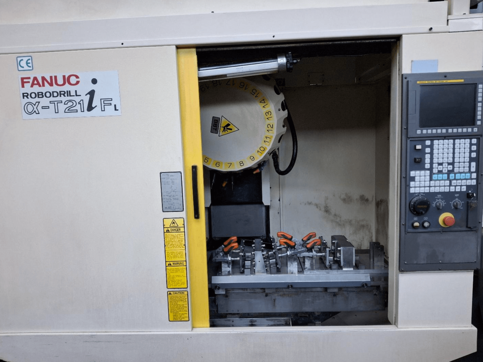 FANUC ROBODRILL α-T21iFL -pystytyöstökeskuksen etukuva, jossa näkyy työkalut ja hallintalaitteet konekaapin sisällä.
