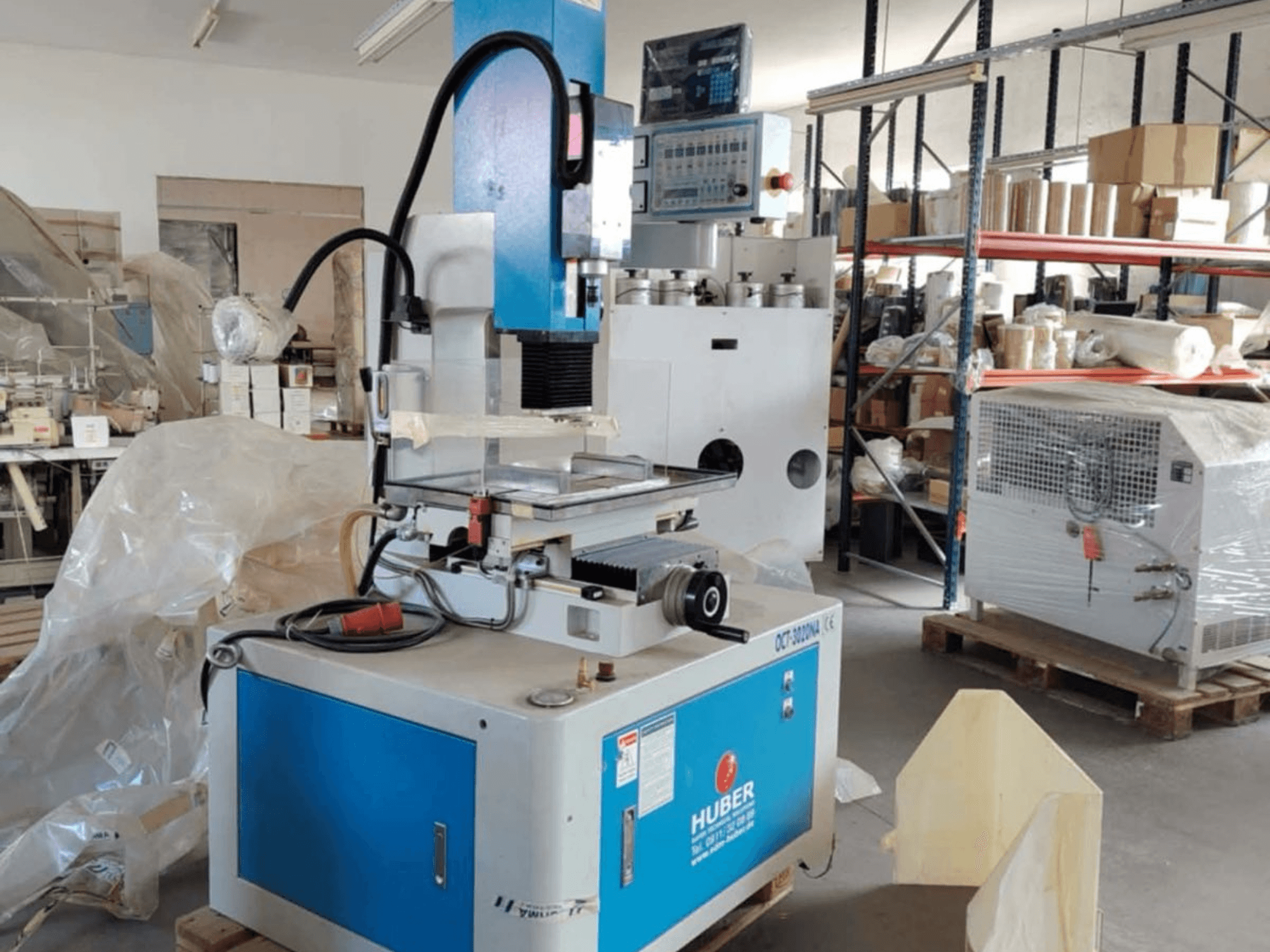HUBER OCT-3020 NA-ruuvisorvaussorvauskone työpajassa, etukuva, jossa näkyy sininen ja harmaa kotelo, digitaaliset hallintalaitteet ja työskentelyalue.