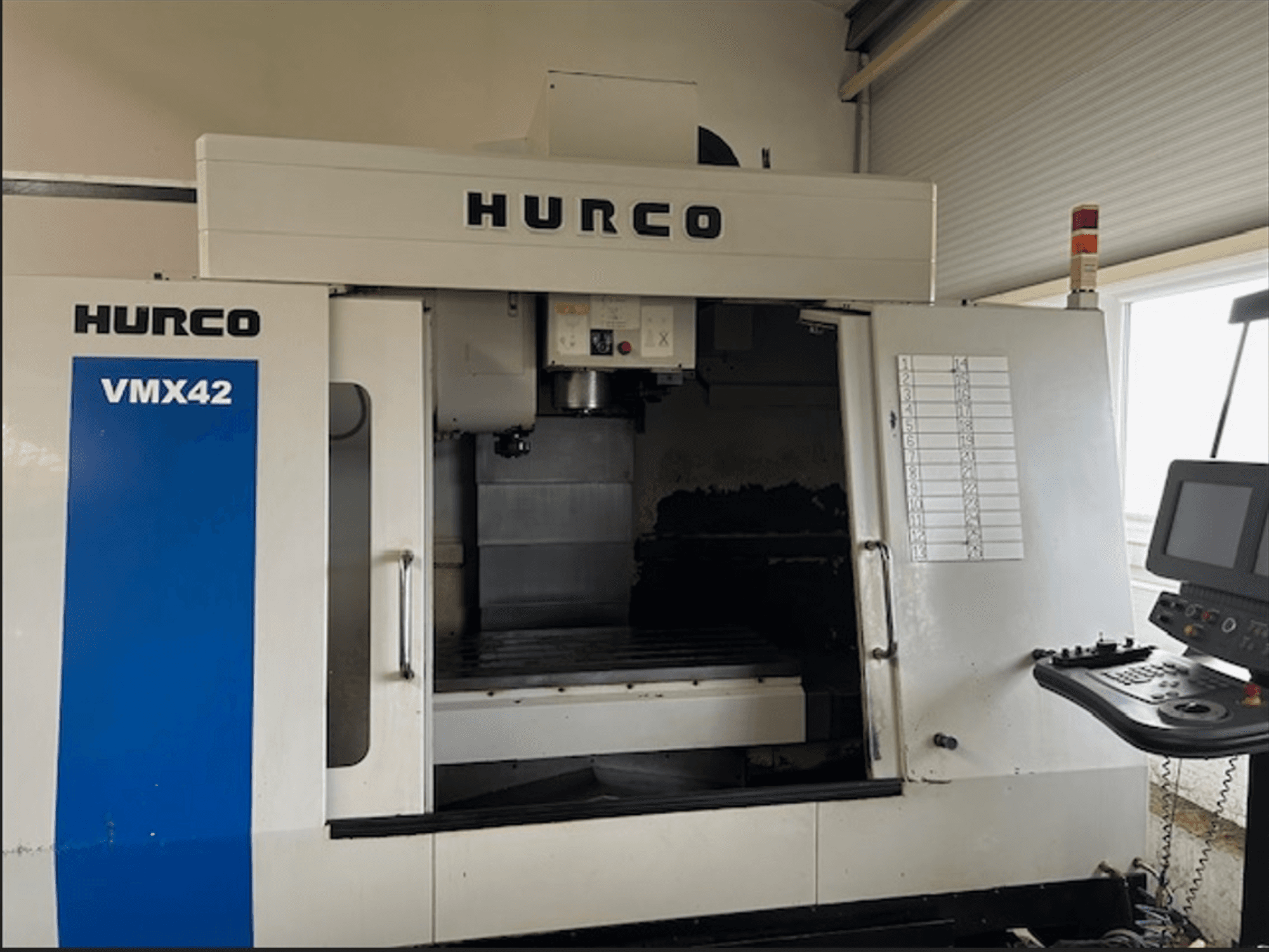 Hurco VMX42 CNC-jyrsinkone, etukuva, jossa on ohjauspaneeli ja avoin työtila työstötoimintoja varten.