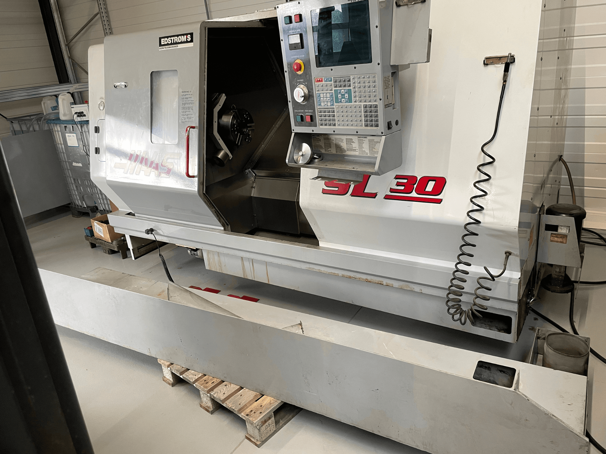 Haas SL 30 CNC-sorvi työpajassa, sivukuva, jossa on ohjauspaneeli ja avoin kara työstötöitä varten.
