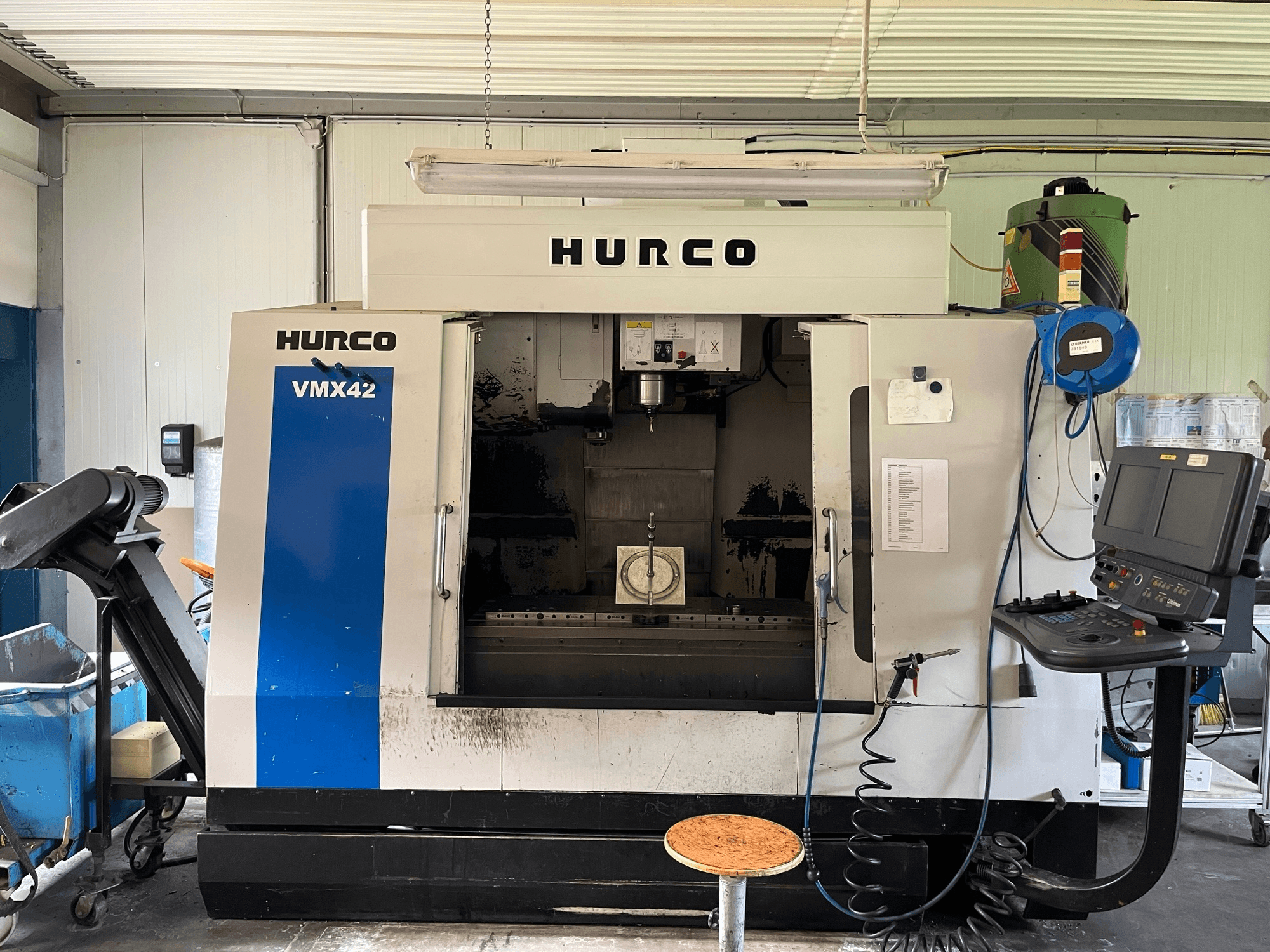 Hurco VMX 42 -pystytyöstökeskus sivukuvassa, jossa näkyy ohjauspaneeli, kara ja työkappaleen asetukset.