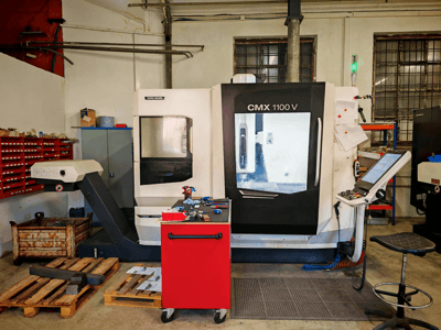 DMG MORI CMX 1100 V -pystykoneistuskeskus työpajassa, etunäkymä, jossa näkyy ohjauspaneeli ja sen ympärillä olevat työkalut.