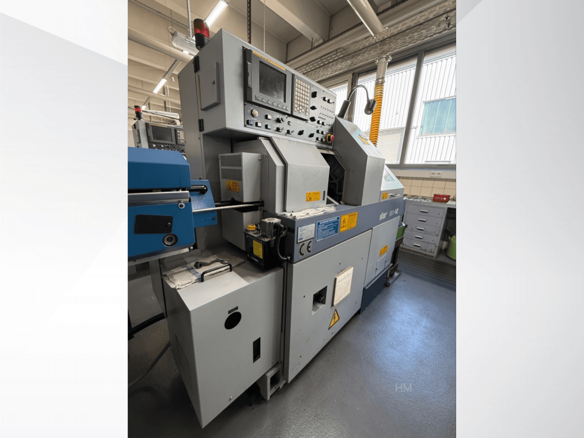 Etukuva lithec 3231 -koneesta, jossa näkyy ohjauspaneeli, moottori ja sininen syöttöosa hyvin valaistussa teollisuusympäristössä.