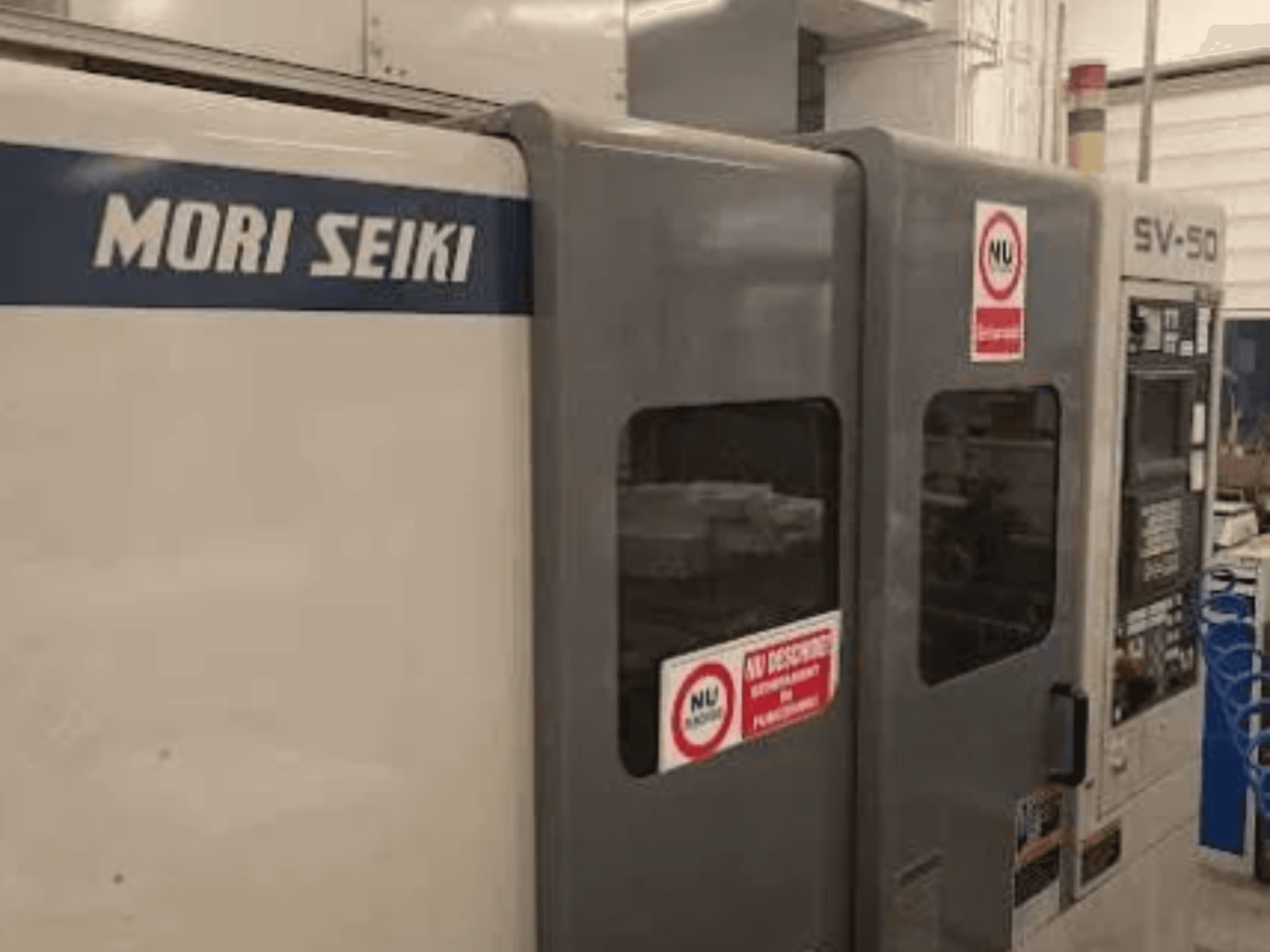 MORI SEIKI SV-50 CNC-kone, sivukuva; ohjauspaneeli ja varoitustarrat.