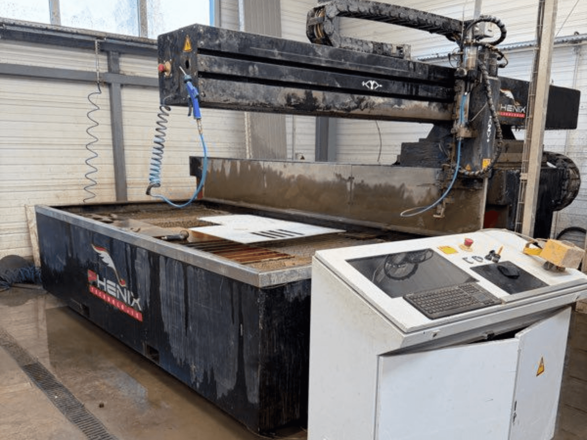 PHENIX MD JET 1530 -vesisuihkuleikkauskone, etukuva, jossa näkyy ohjauspaneeli ja leikkausalue sekä näkyvä vesisäiliö.