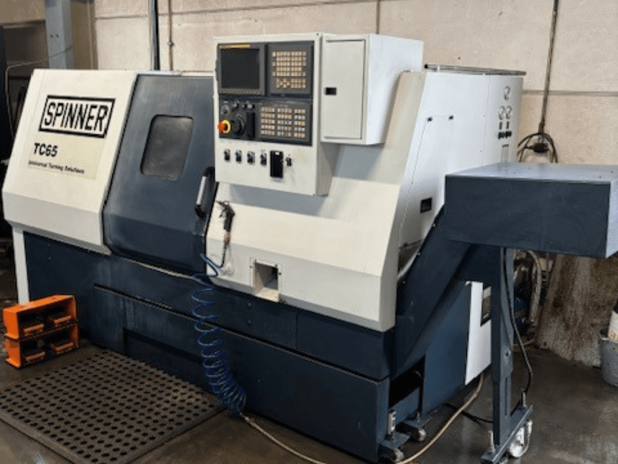 Spinner TC65 -teollisuussorvauskone, etukuva, jossa on ohjauspaneeli, paineilmalinja ja työkalujen säilytystila.