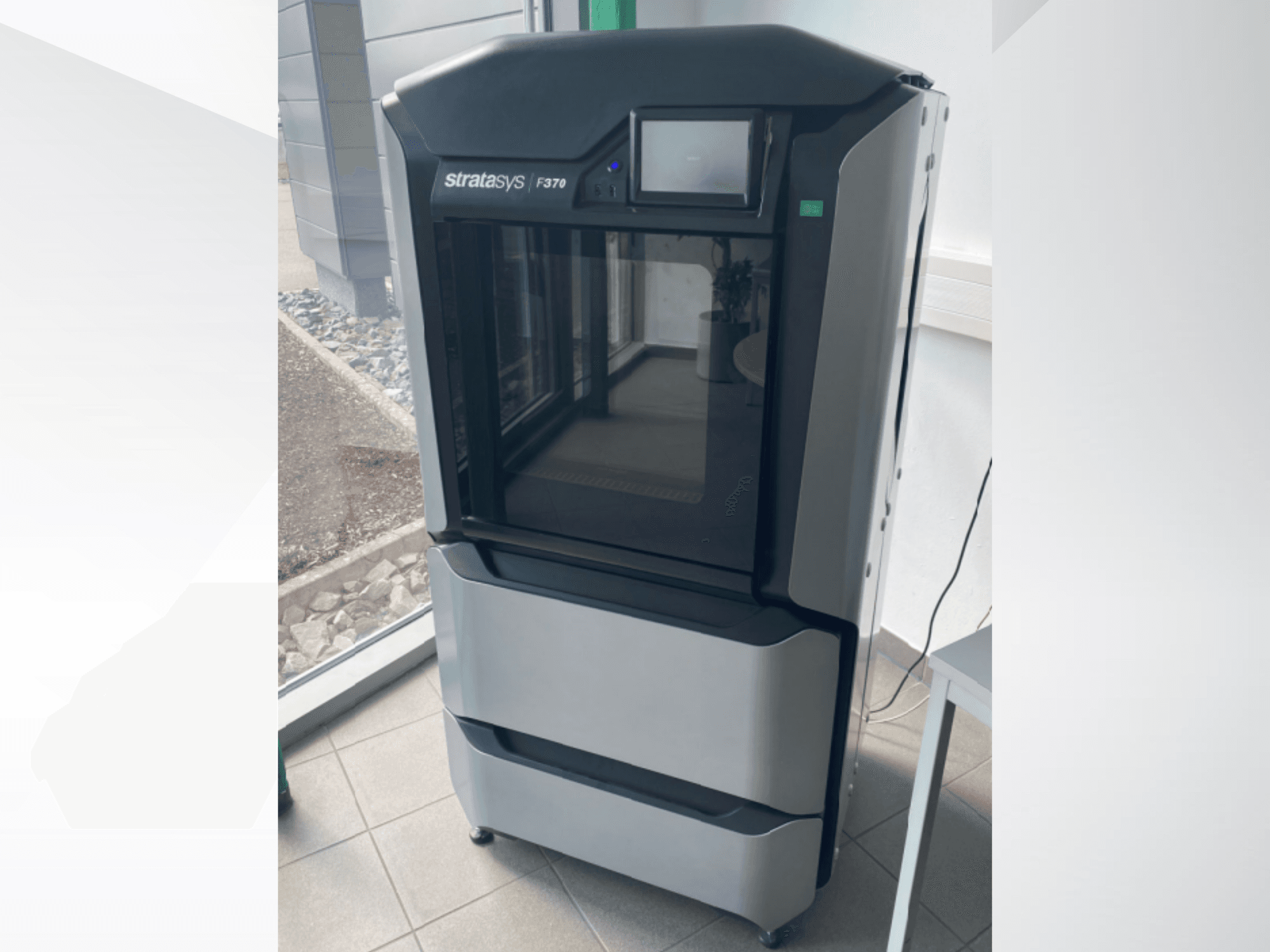 Stratasys F370 -muovinen 3D-tulostin, etukuva, jossa on tyylikäs musta ja harmaa muotoilu ja kosketusnäyttö.