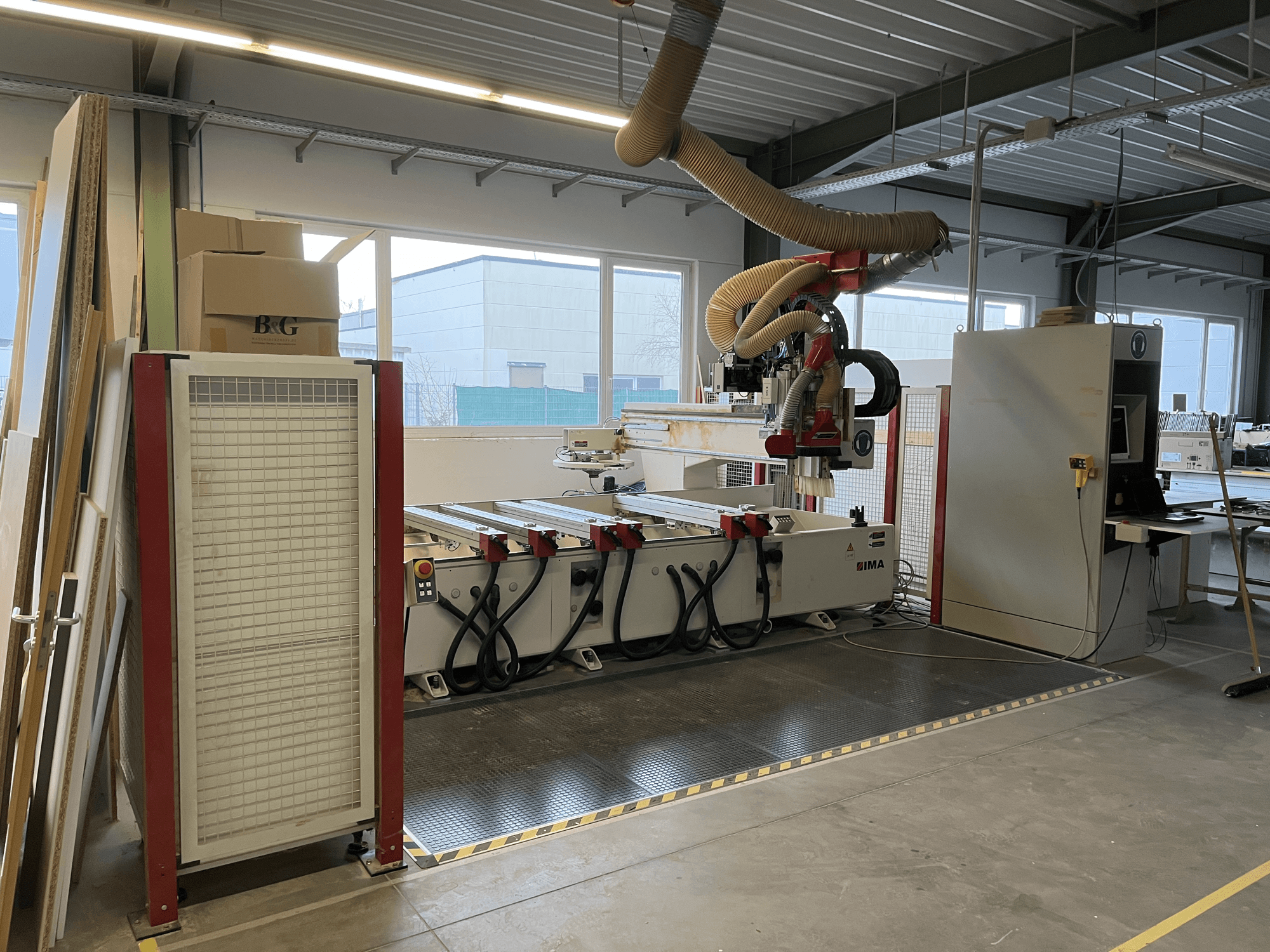 CNC-puuntyöstökeskus IMA BIMA 410 työpajassa, sivukuva, jossa ohjauspaneeli ja pölynpoistojärjestelmä näkyvissä.