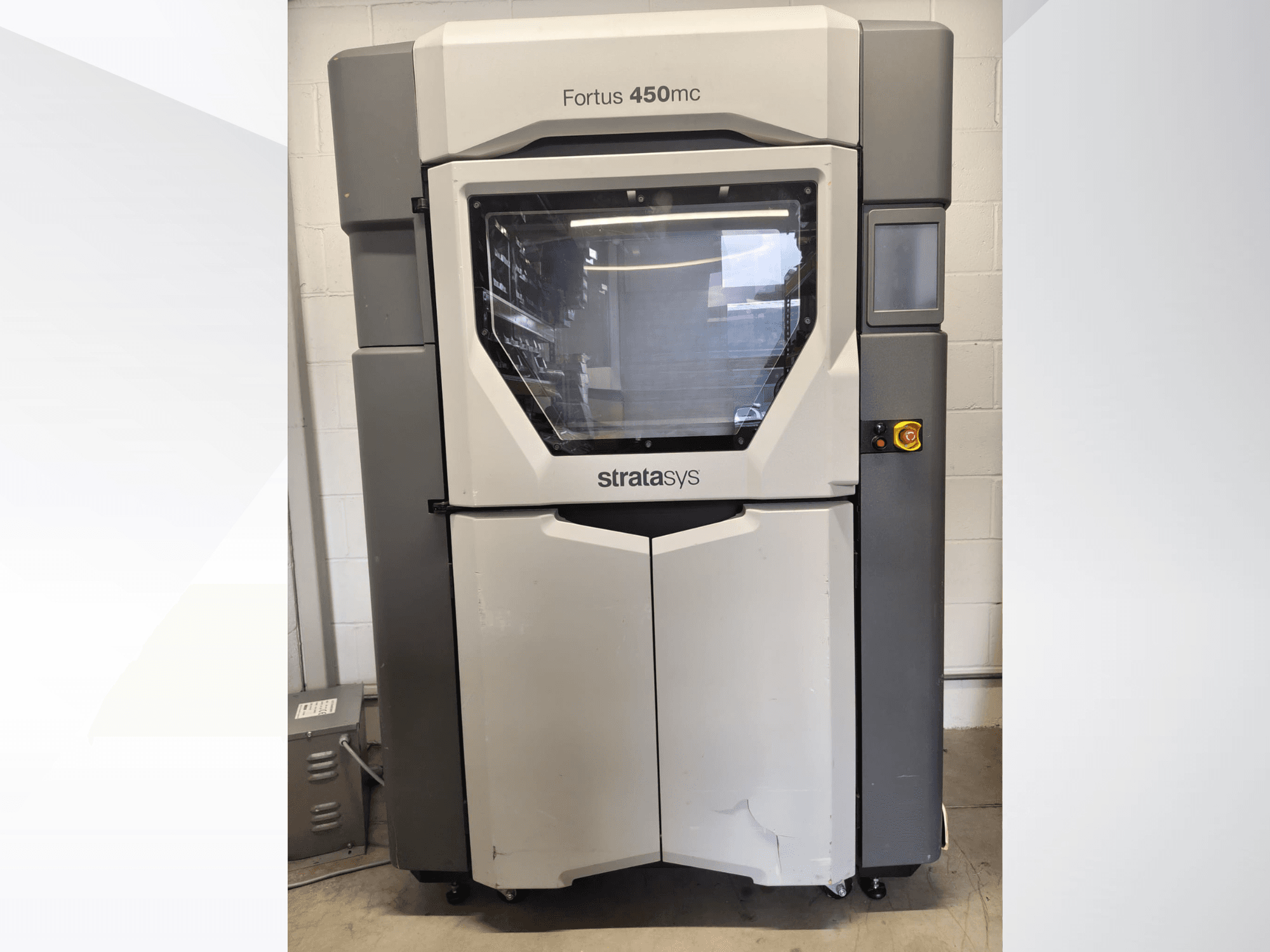 Stratasys Fortus 450mc -muovikäsittelykone, etunäkymä, jossa on suuri ikkuna, ohjauspaneeli ja teollinen muotoilu.