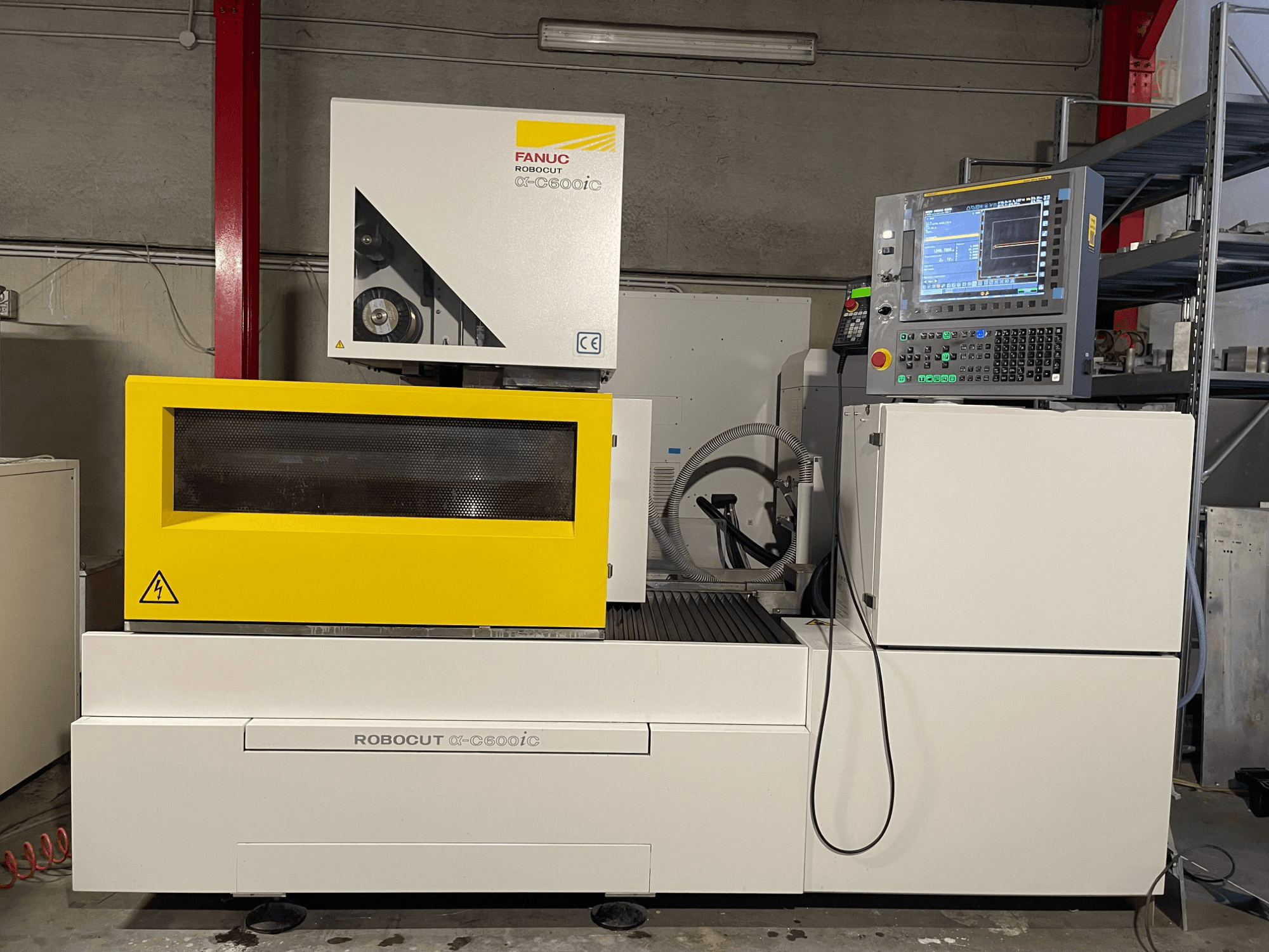 FANUC Robocut α-C600iC, sivukuva CNC-koneesta, jossa on keltainen suojakansi ja ohjauspaneeli ja joka esittelee tarkkuusleikkauskykyä.