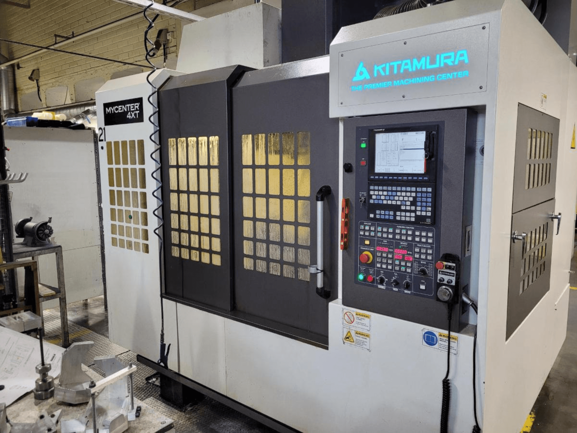 Pystykuva Kitamura Mycenter-4XT -työstökeskuksesta, jossa on ohjauspaneeli ja valaistu tuotemerkki.